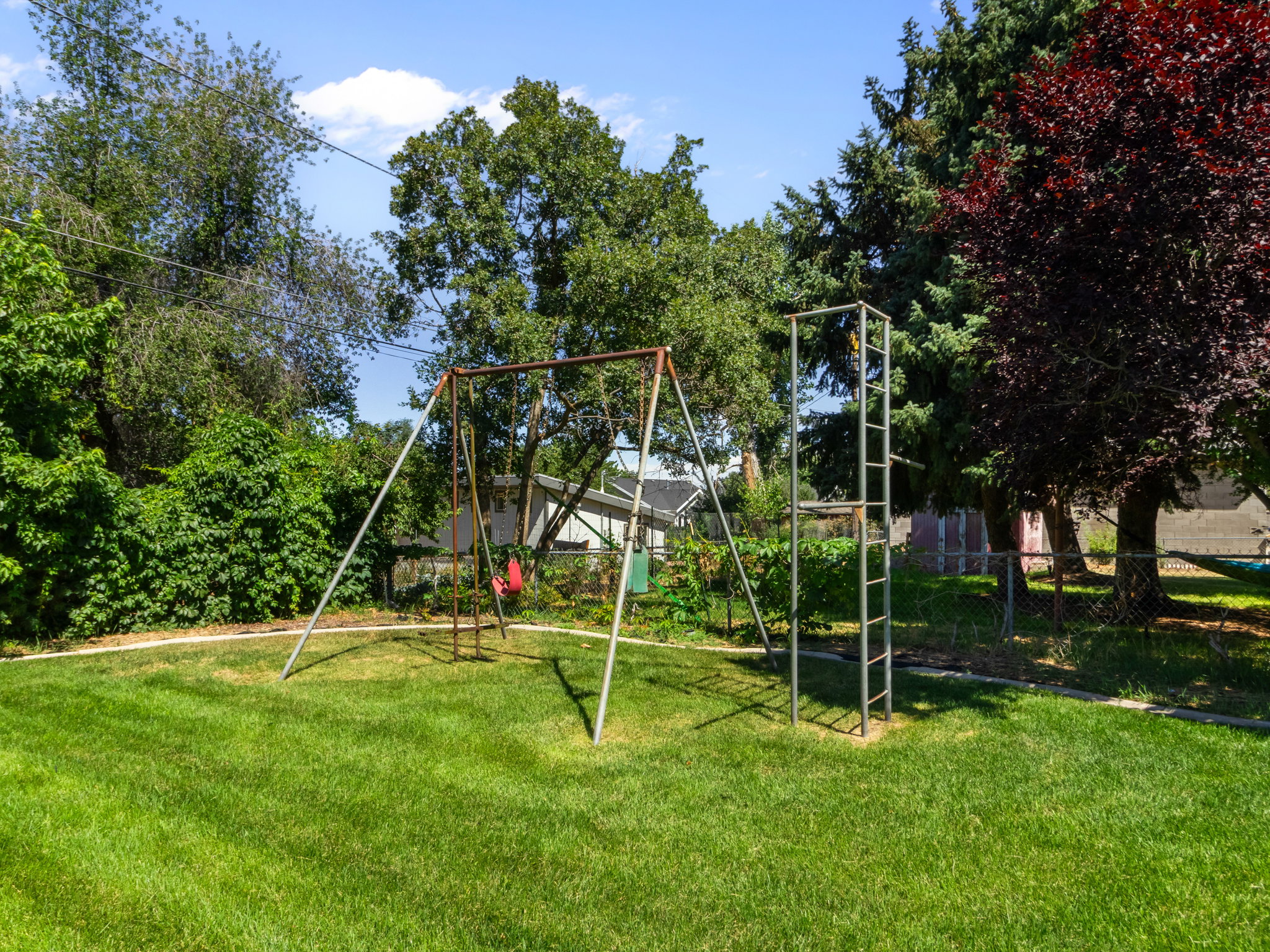 Expansive lawn area featuring a metal swing set and a climbing structure