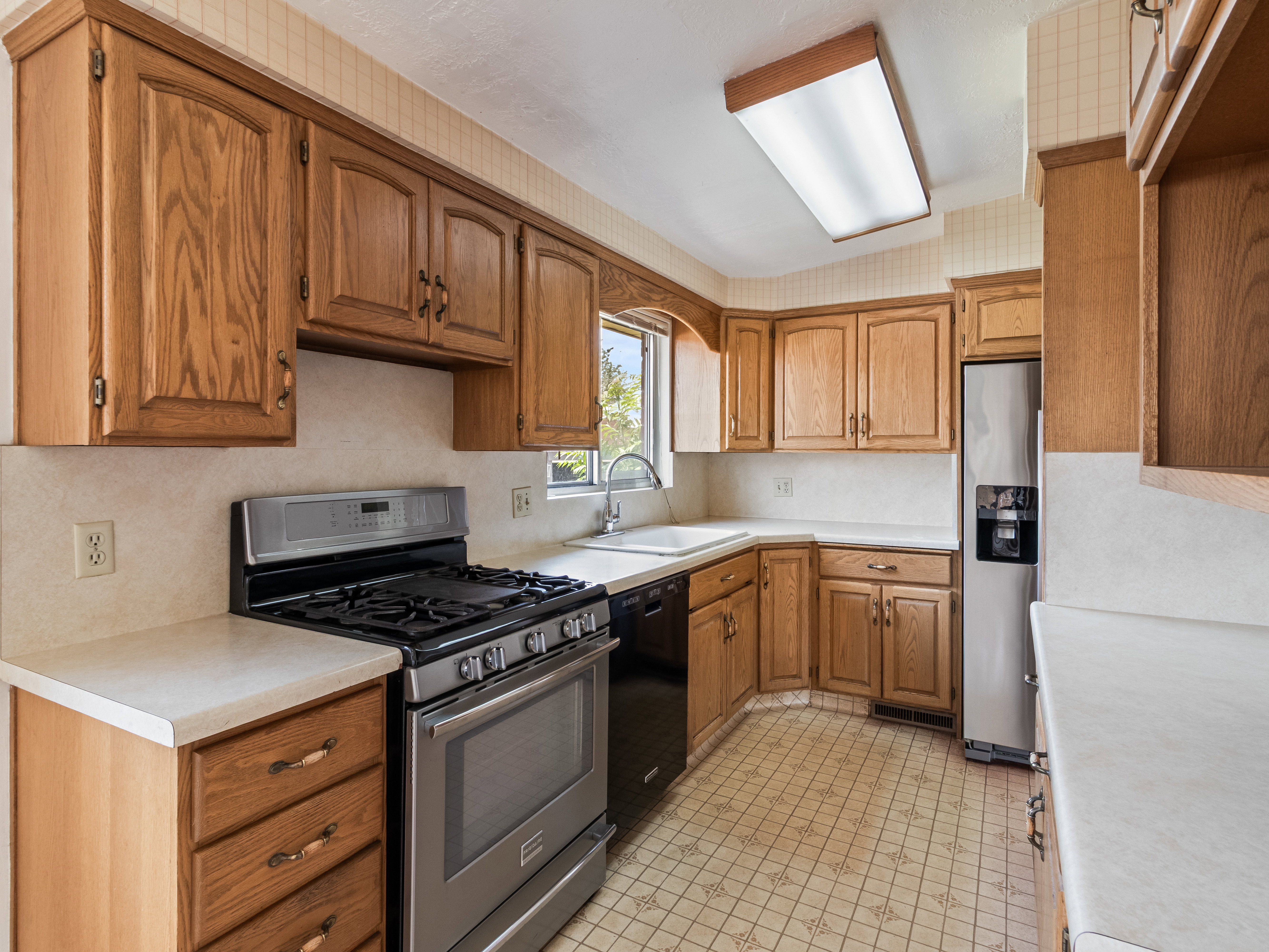 Kitchen featuring wood cabinetry, stainless steel appliances, a gas range, and a double basin sink