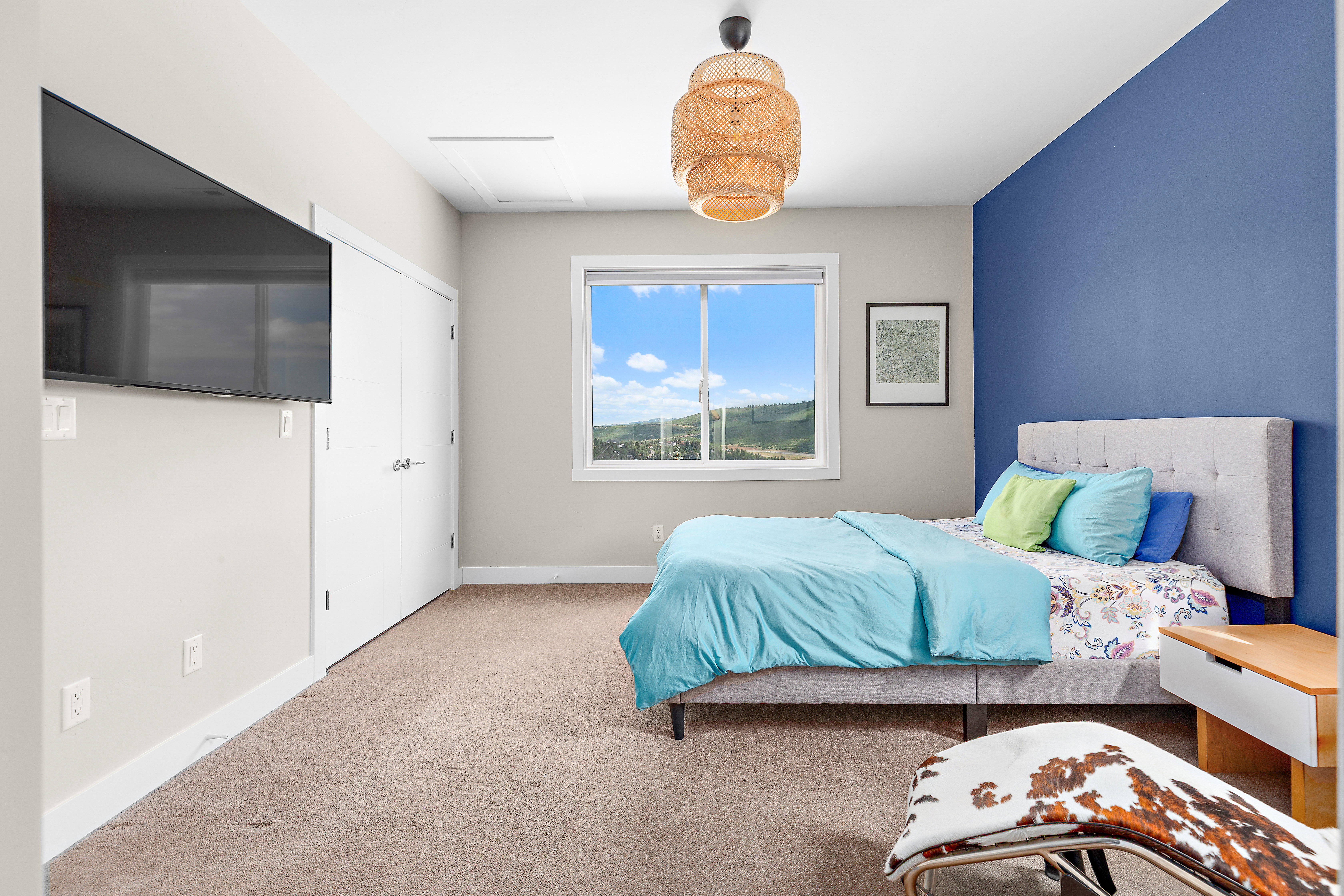 Bright bedroom with a large window, offering distant landscape scenery