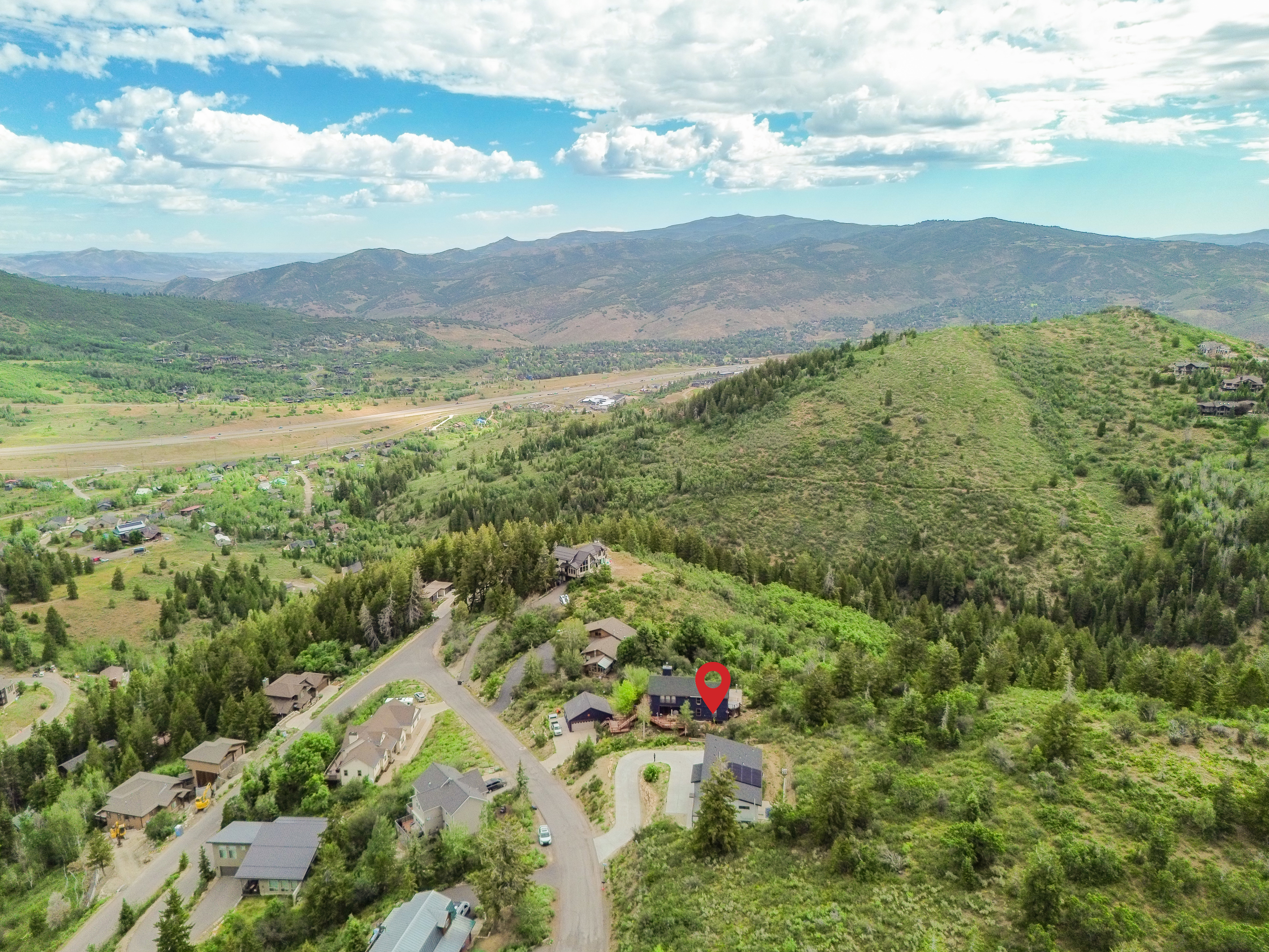 Expansive mountain landscape featuring a winding road and a residential property with a dark-colored exterior