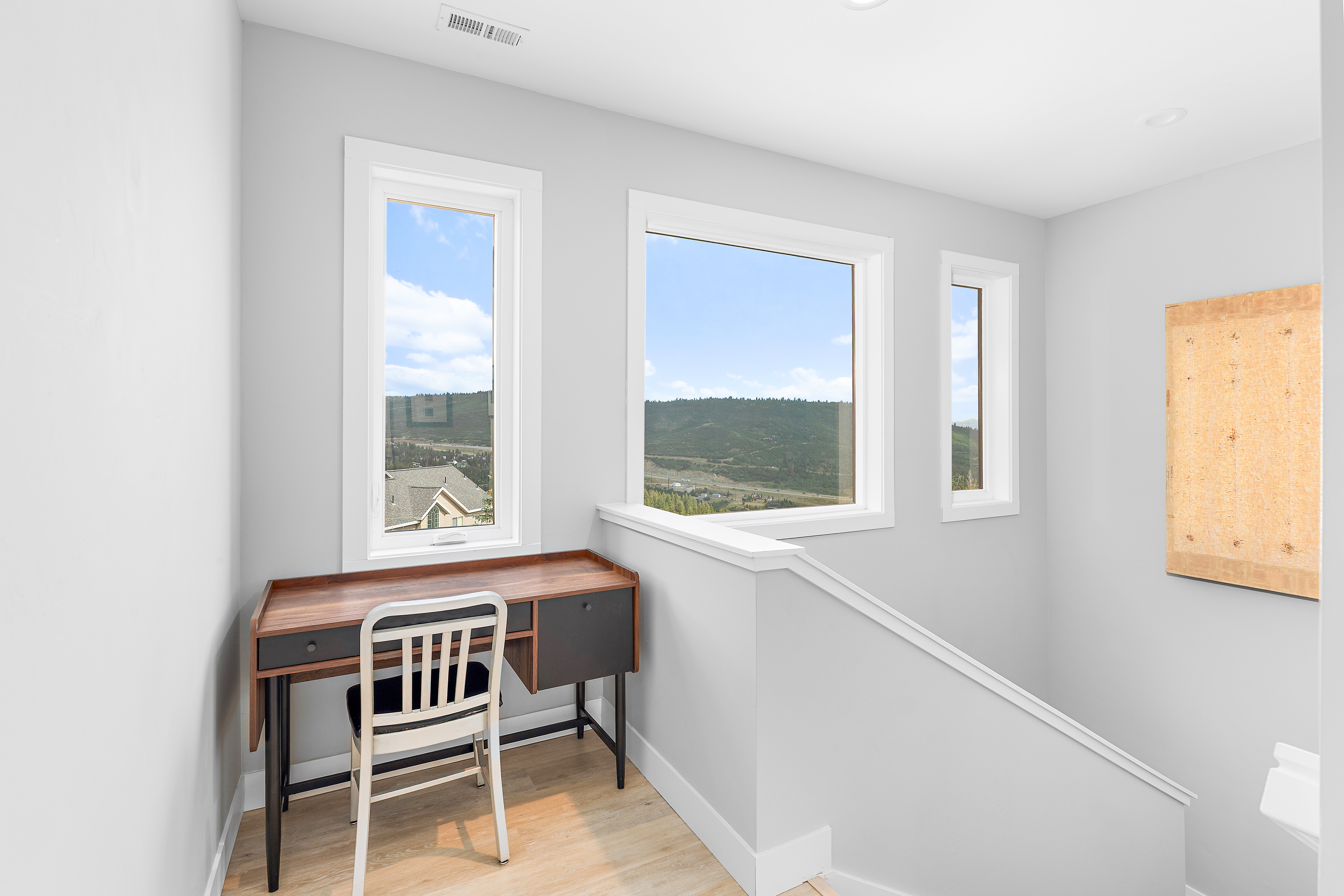 Bright loft area featuring multiple windows, light wood-finish flooring, white baseboards, and a contemporary railing