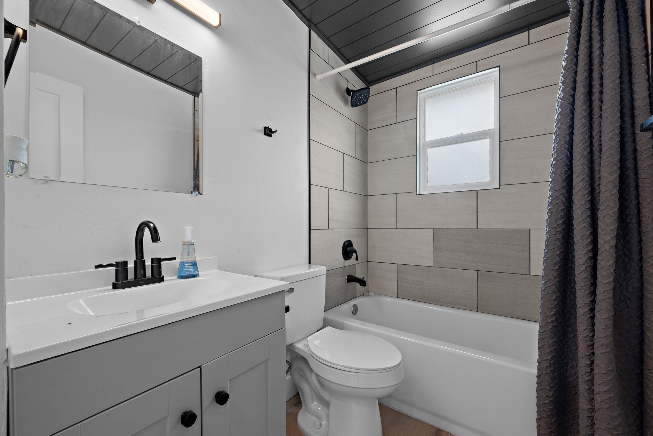 Bathroom featuring a white vanity with a rectangular sink, matte black faucet, and a large mirror