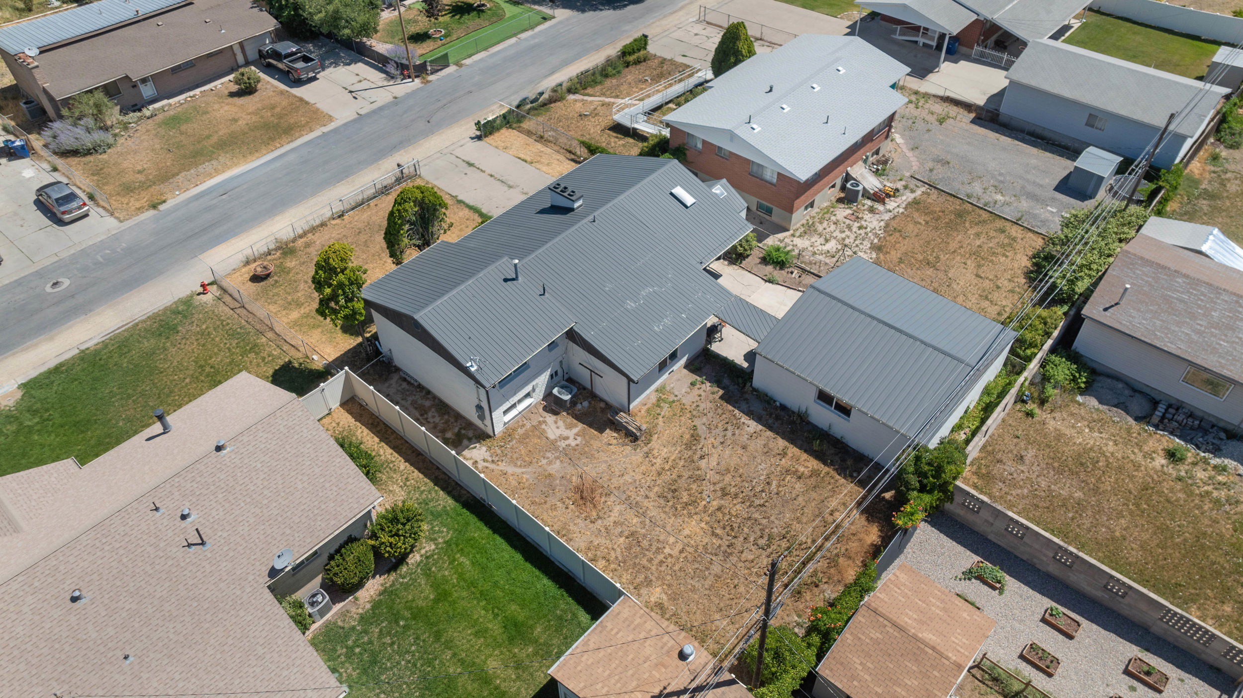 Property featuring a gray metal roof, attached garage, and a separate detached garage structure