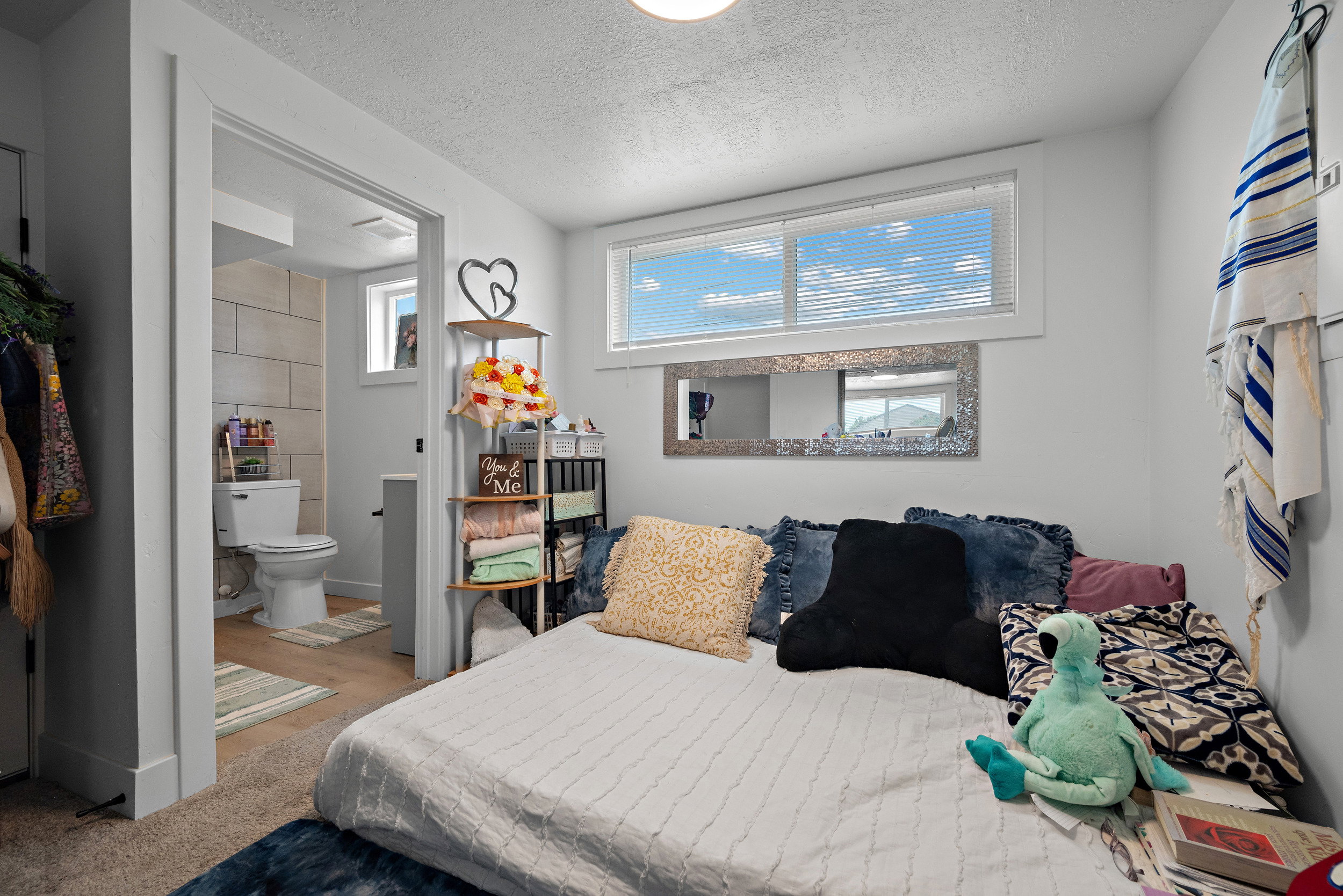 Bedroom featuring natural light from a horizontal window with blinds, light-colored walls, and carpeting