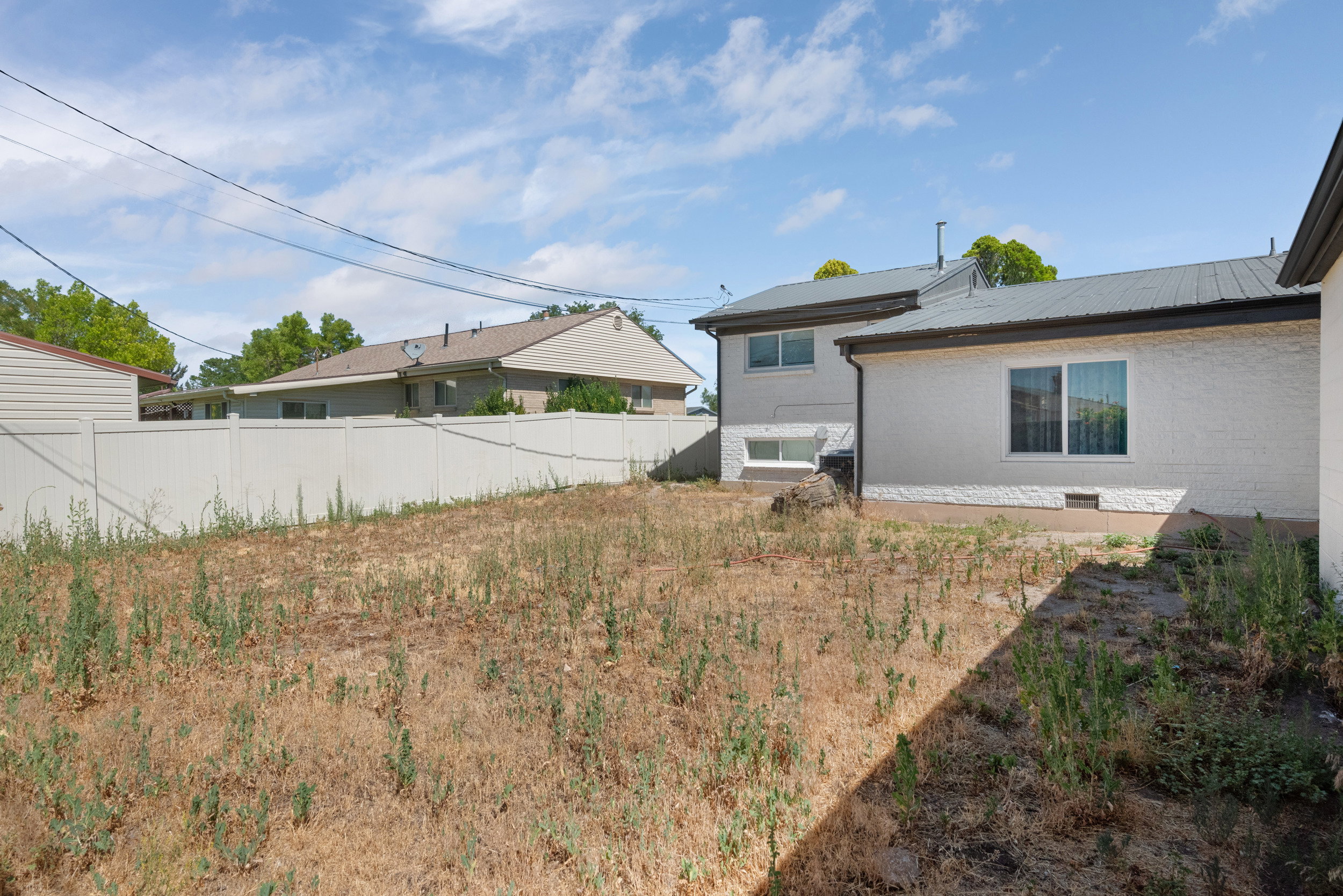 Expansive backyard space with a white privacy fence