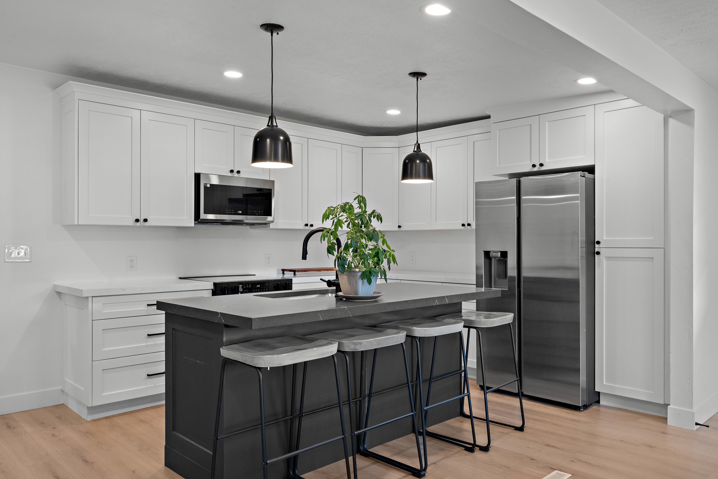 Modern kitchen featuring a central island with seating, white shaker cabinetry, stainless steel appliances, and pendant lighting