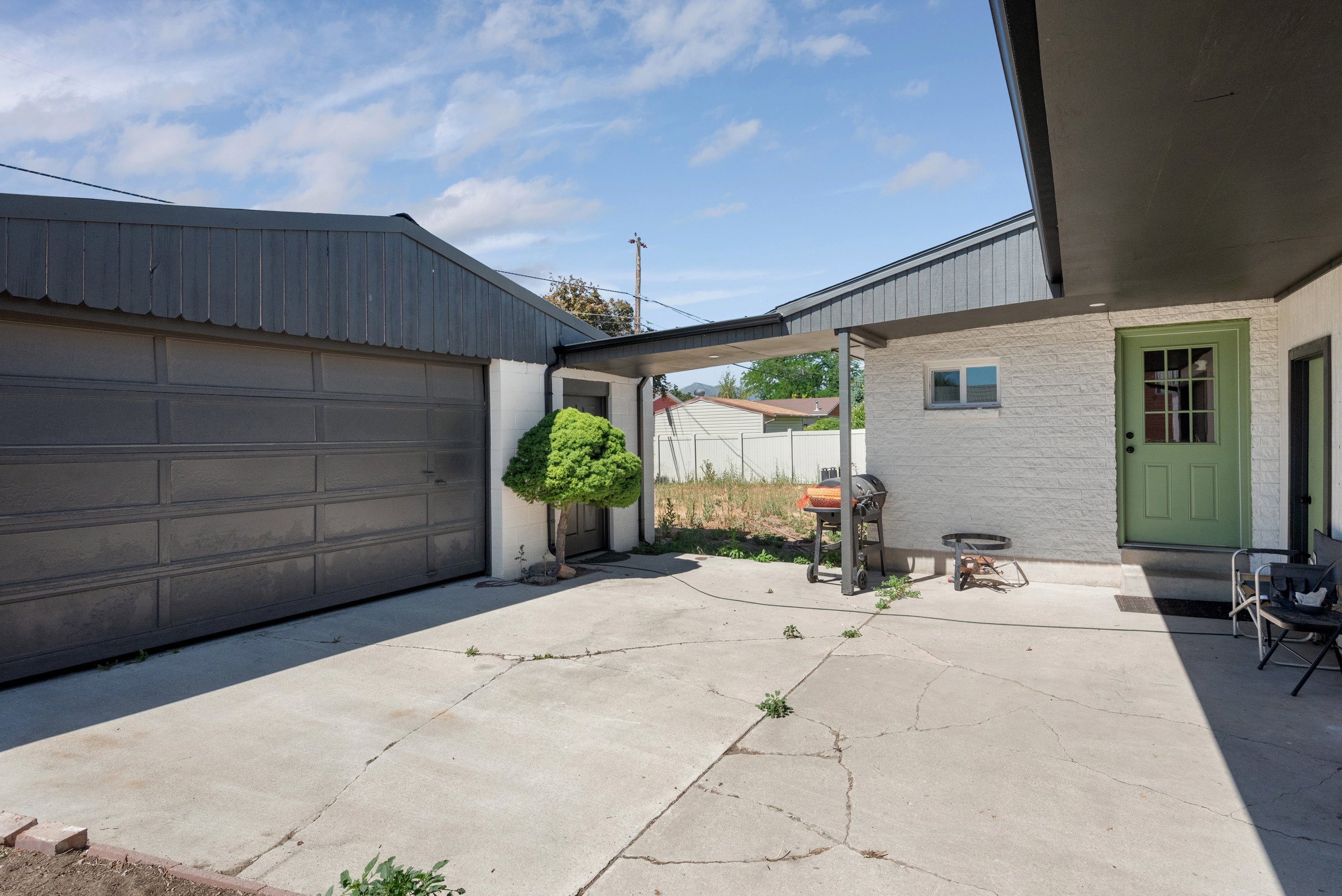 Concrete patio area featuring an attached garage with a dark paneled door and a covered entryway