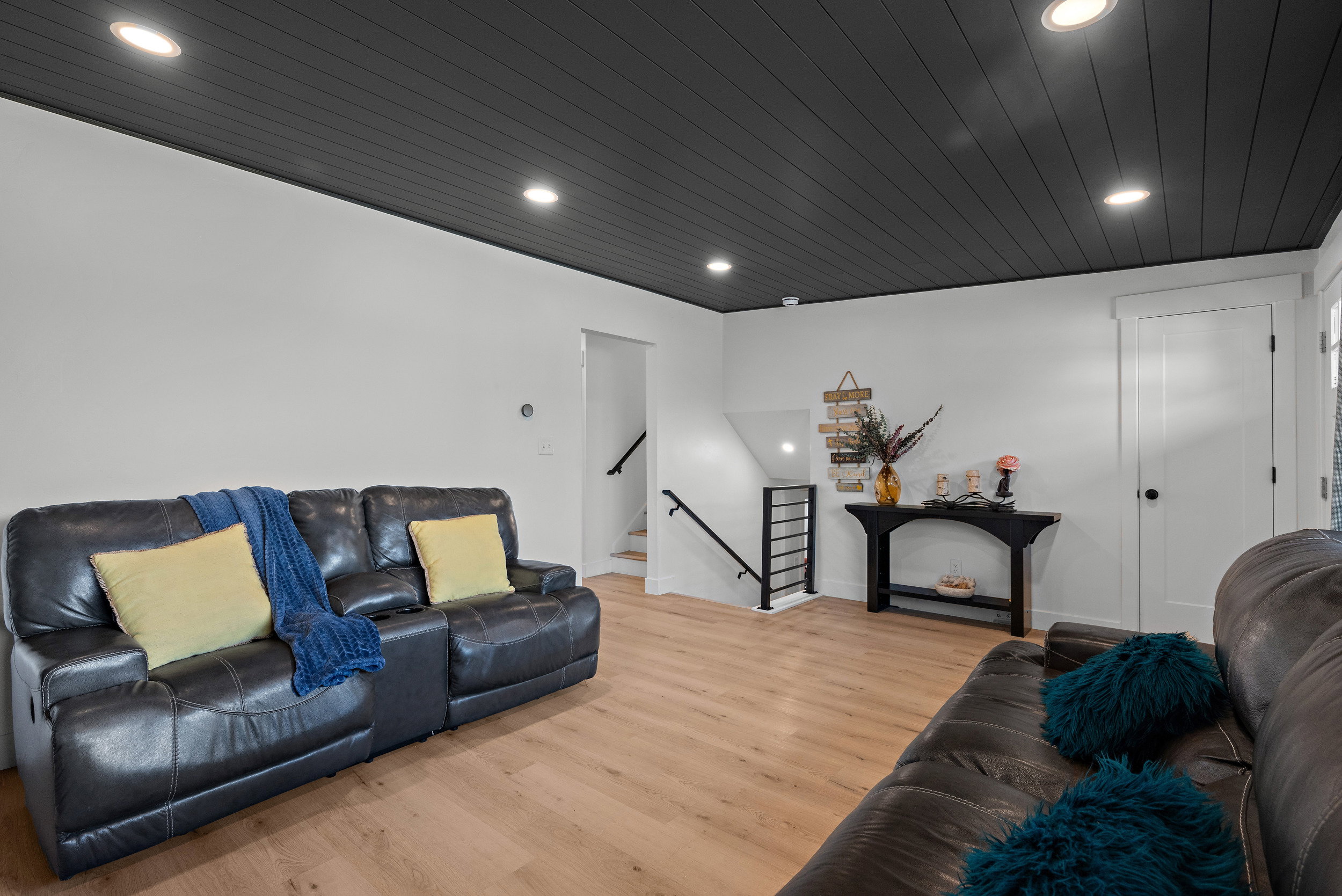 Room featuring light wood-finish flooring, white walls, and a distinctive dark paneled ceiling with recessed lighting