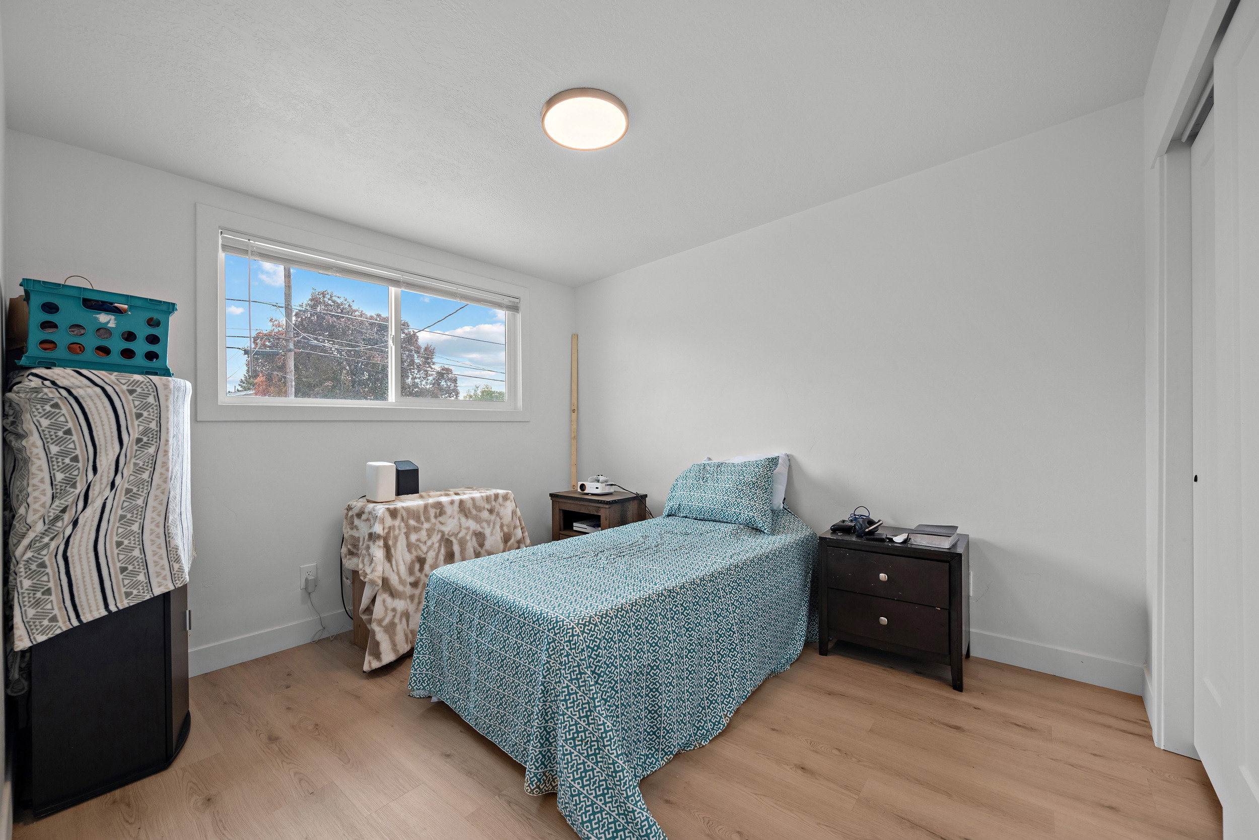 Bedroom featuring wood-finish flooring, a flush-mount ceiling light, and a horizontal window with white trim