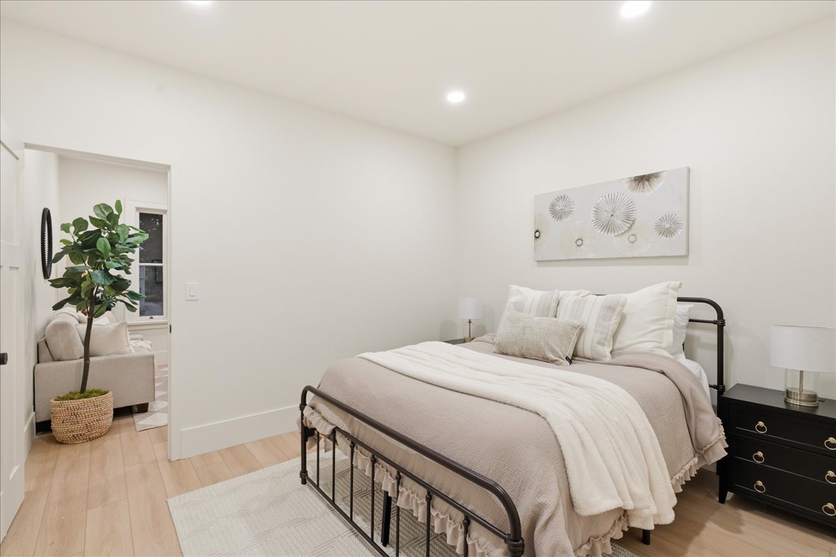 Recessed lighting illuminates this room featuring light wood-finish flooring and pristine white walls