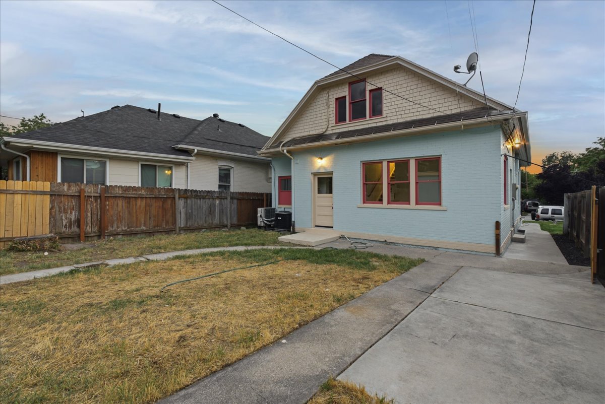 Light blue exterior with red trim accents, featuring a concrete driveway and walkway