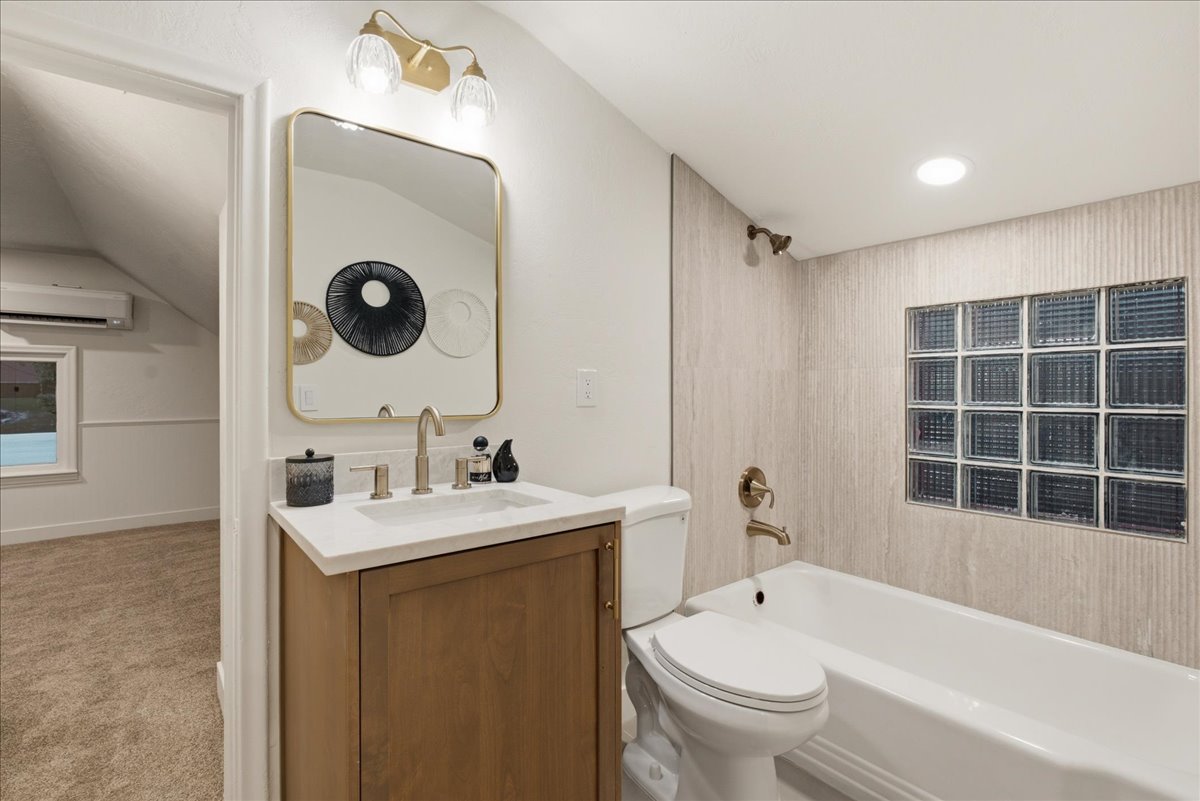 Full bathroom featuring a single vanity with a light wood-finish cabinet, white countertop, and rectangular undermount sink