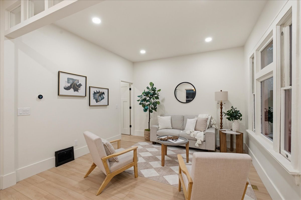 Spacious living area featuring light wood-finish flooring, recessed lighting, and bright white walls