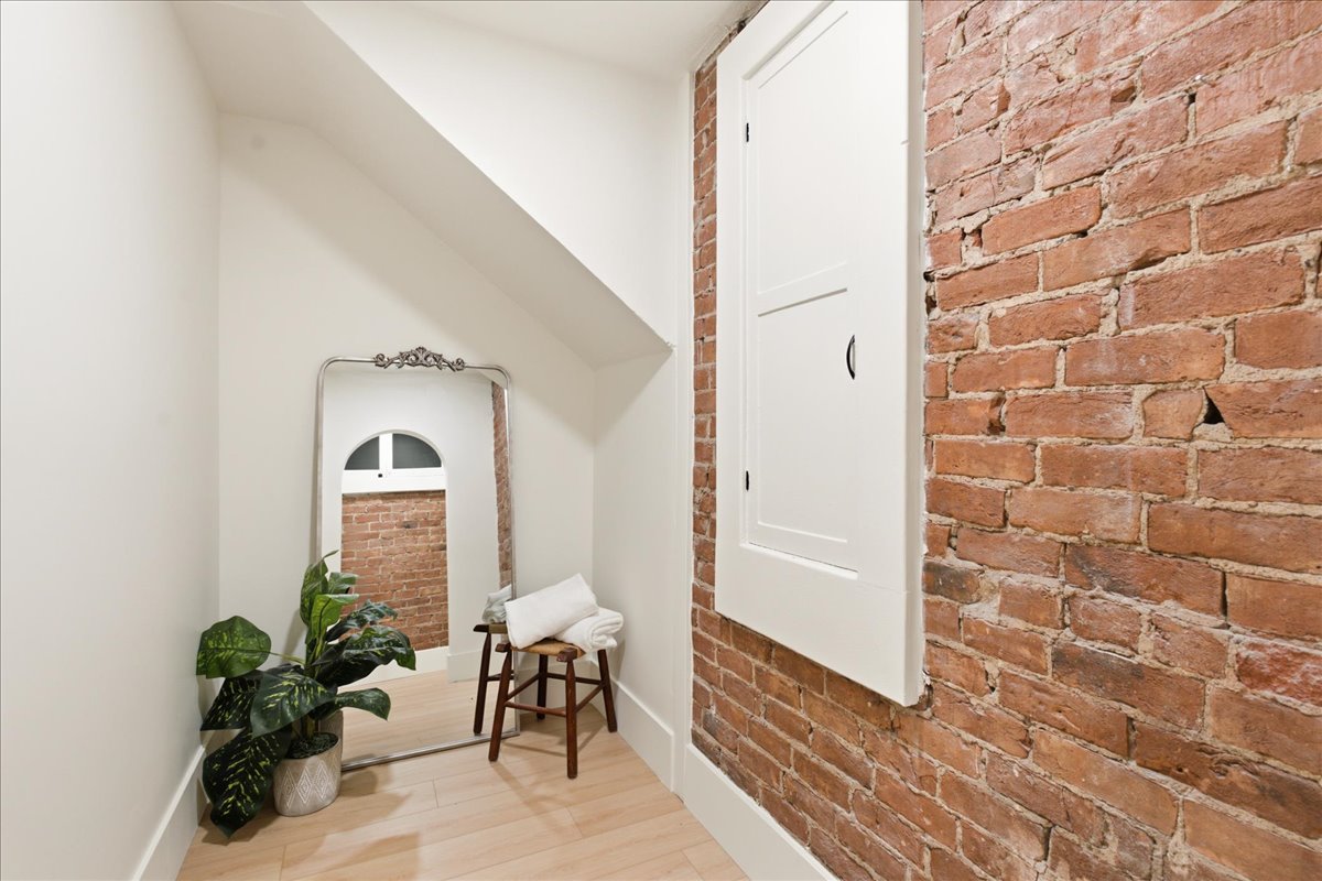 Exposed brick wall detail contrasting with smooth white walls and light wood-finish flooring
