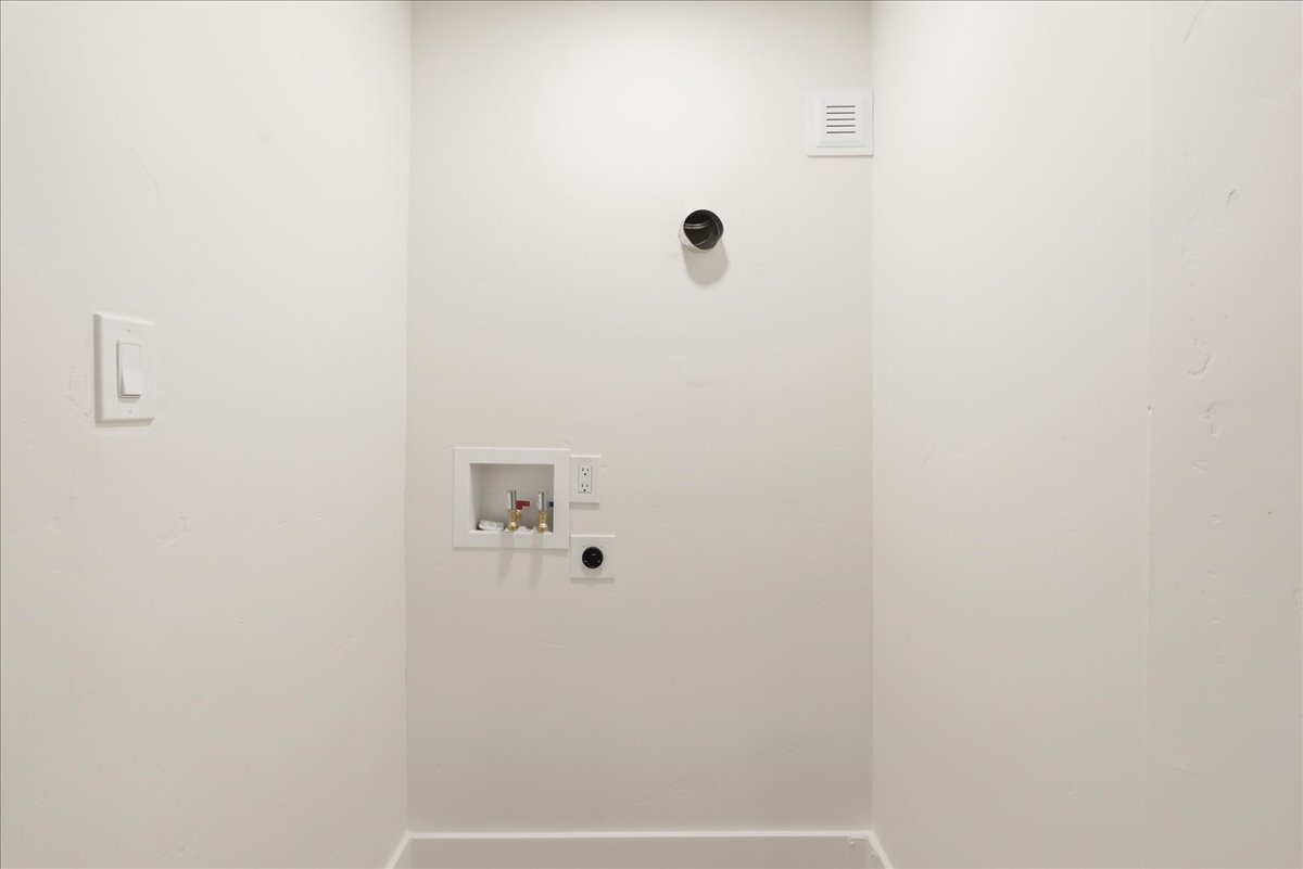 Dedicated laundry appliance hookups featuring water lines, drainage, and electrical outlet