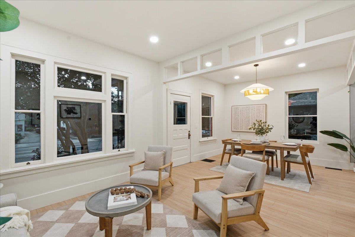 Spacious living area featuring light wood-finish flooring and multiple windows with white trim