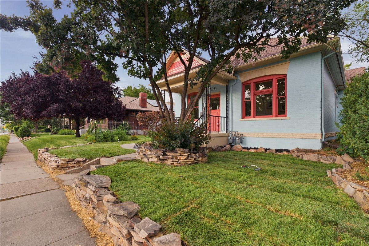 Light blue exterior with red window trim and front door, featuring a covered porch with black railing