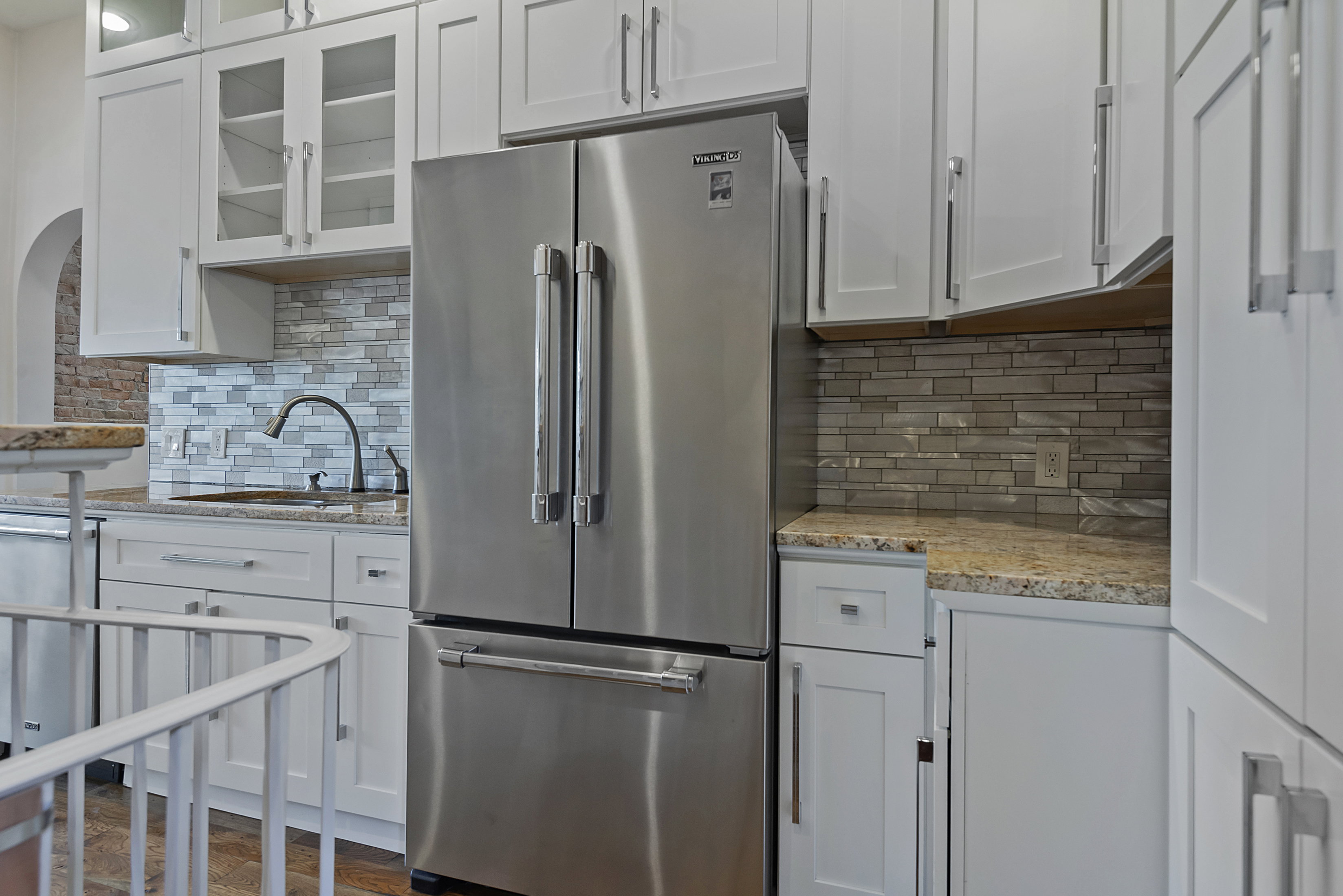 Stainless steel French door refrigerator set amidst white shaker-style cabinetry with brushed nickel hardware
