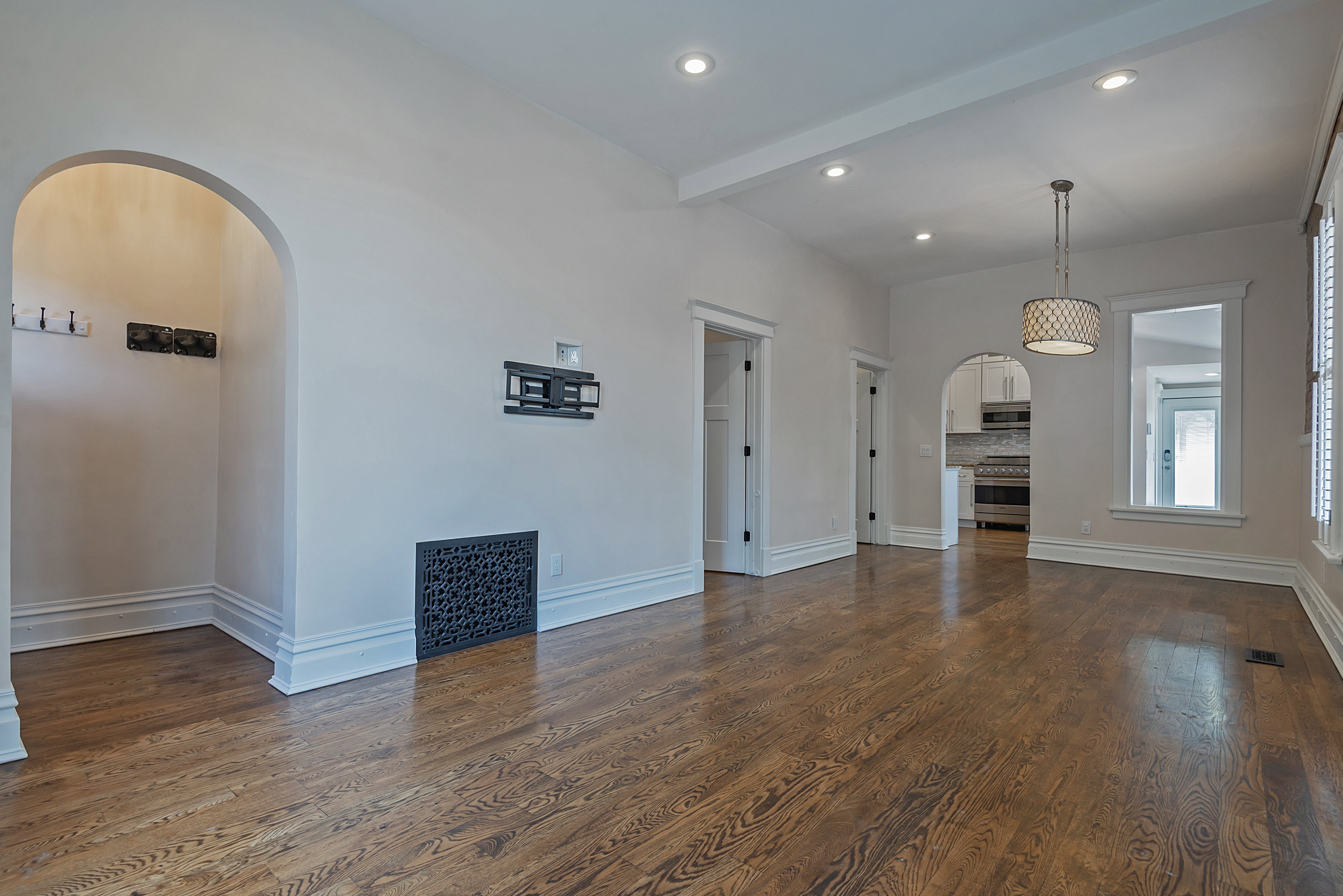 Expansive room featuring rich wood-finish flooring, recessed lighting, a decorative drum pendant light, and white trim throughout