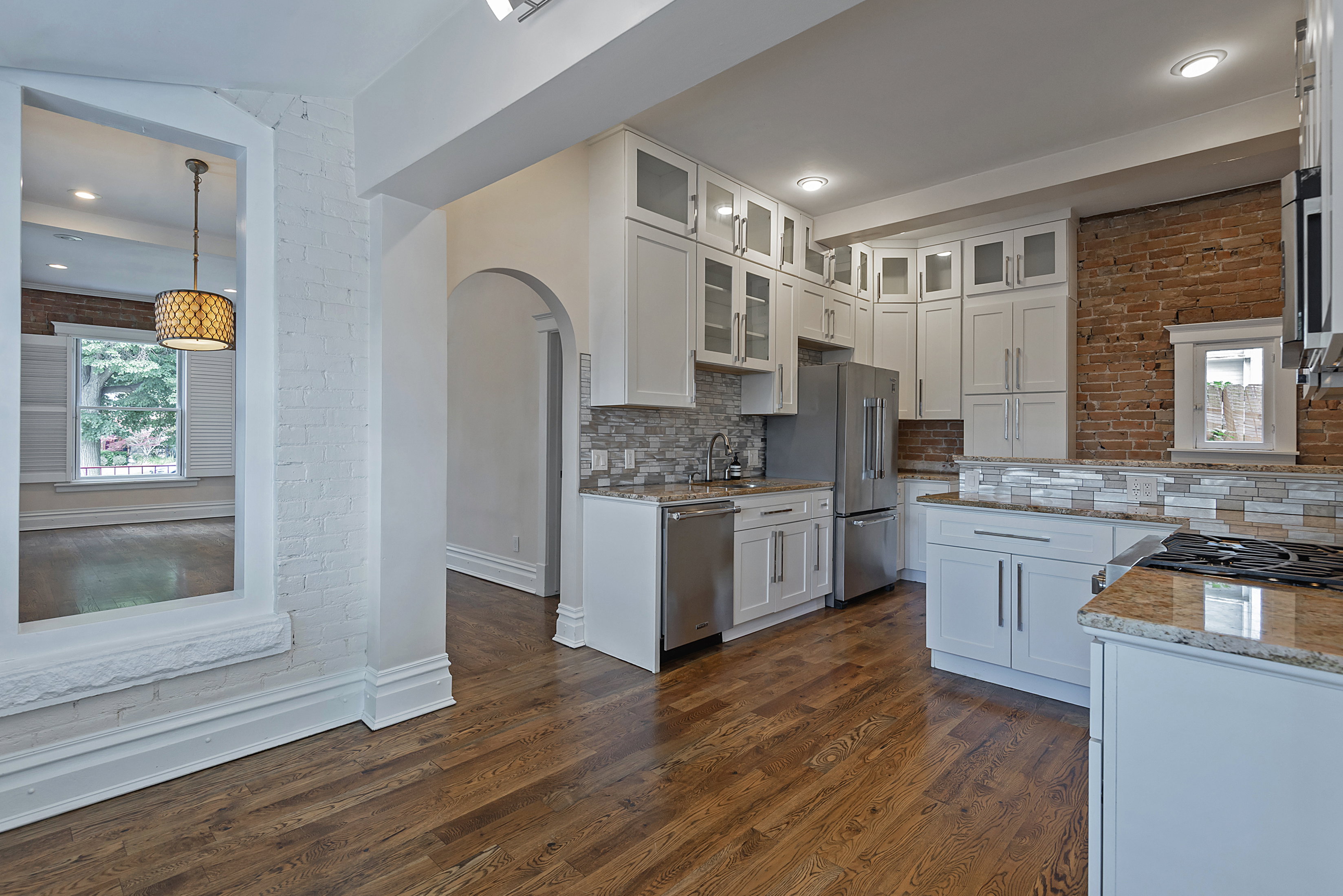 Kitchen featuring white cabinetry with glass inserts, stainless steel appliances, and wood-finish flooring