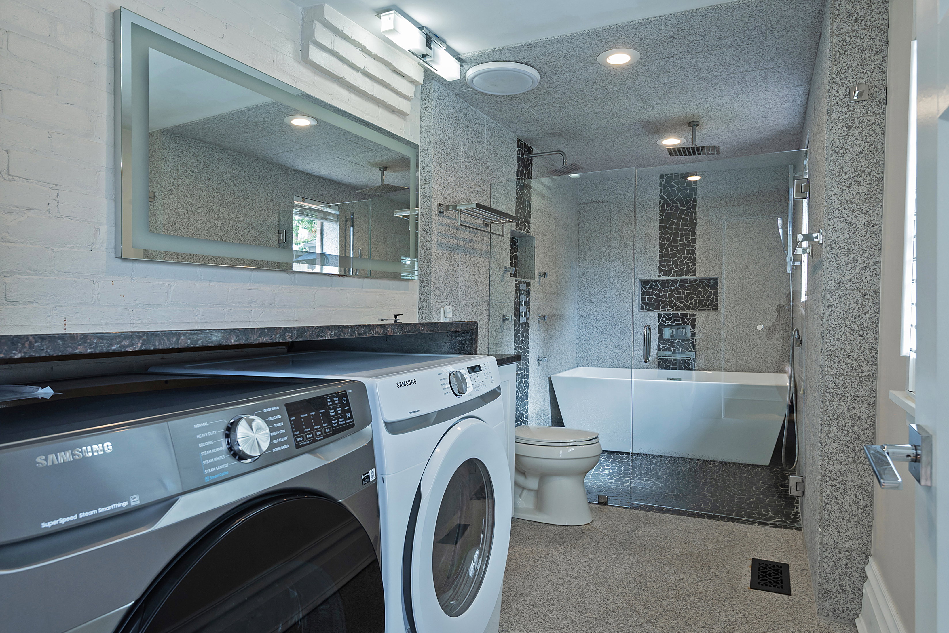 Contemporary full bathroom featuring a freestanding tub, glass-enclosed shower, and built-in laundry