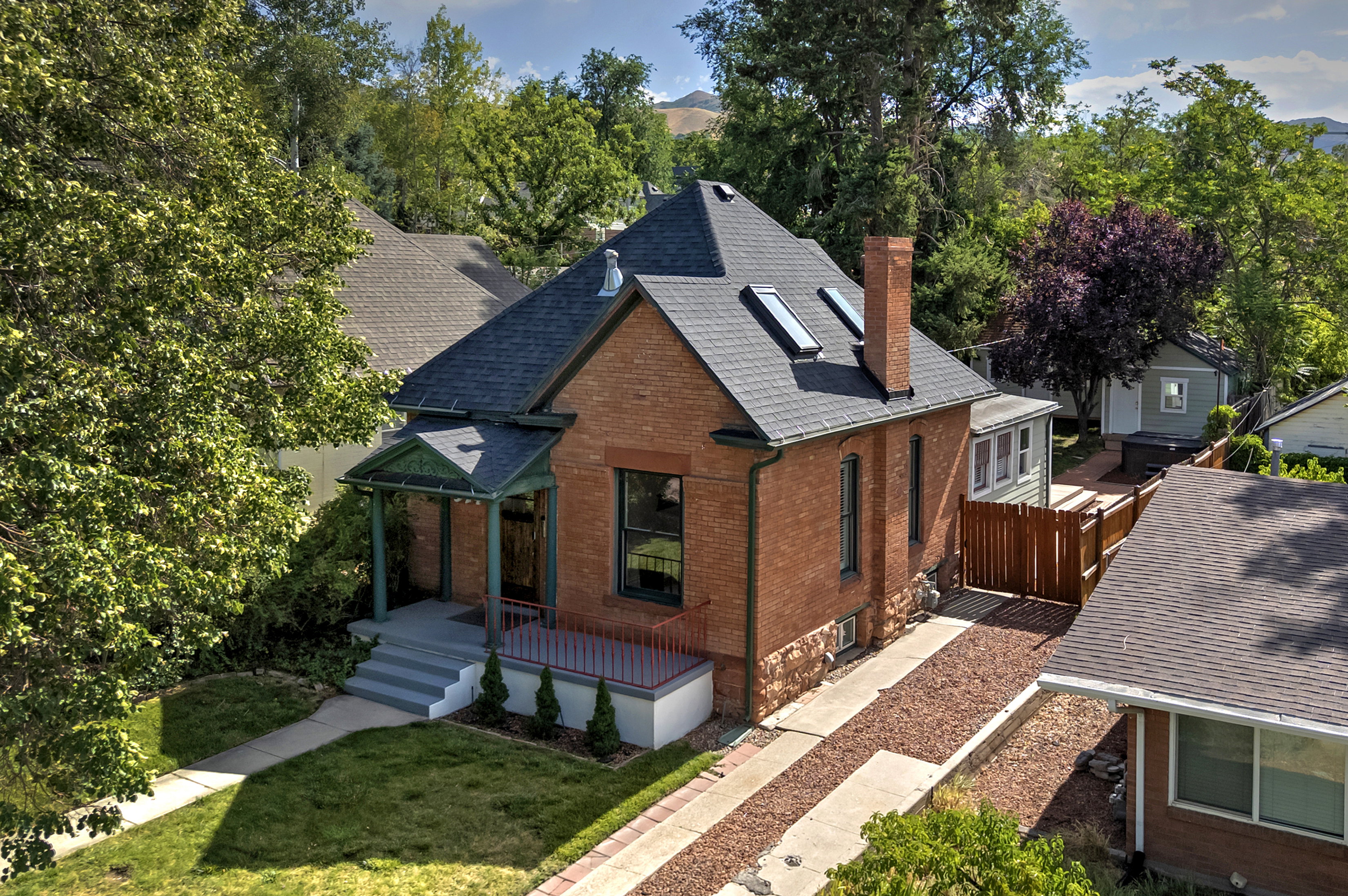 Brick exterior residence featuring a front porch with decorative columns, a steeply pitched roof with skylights, and a prominent brick chimney