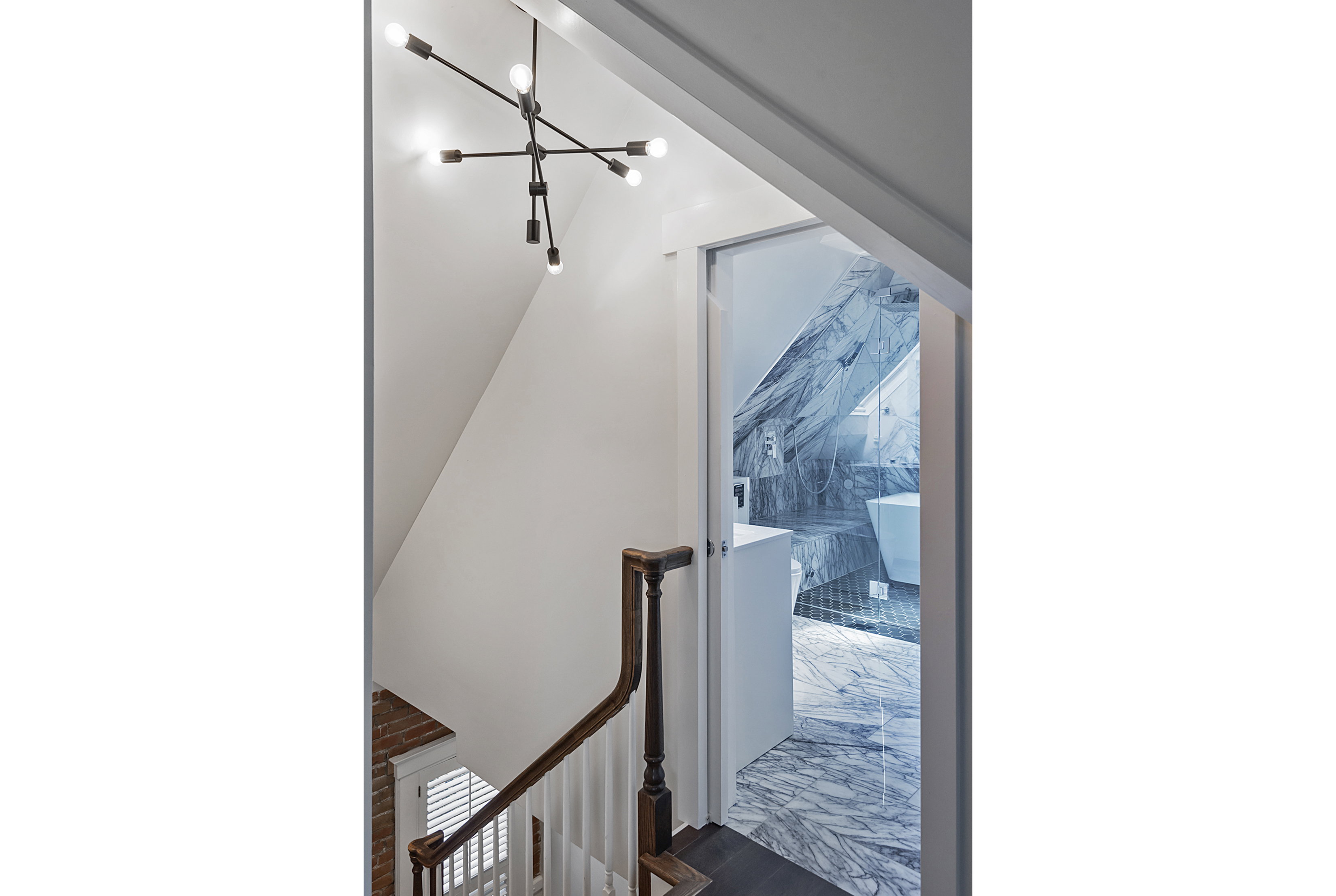 Stairwell featuring a dark wood newel post and handrail, white balusters, and a modern sputnik chandelier