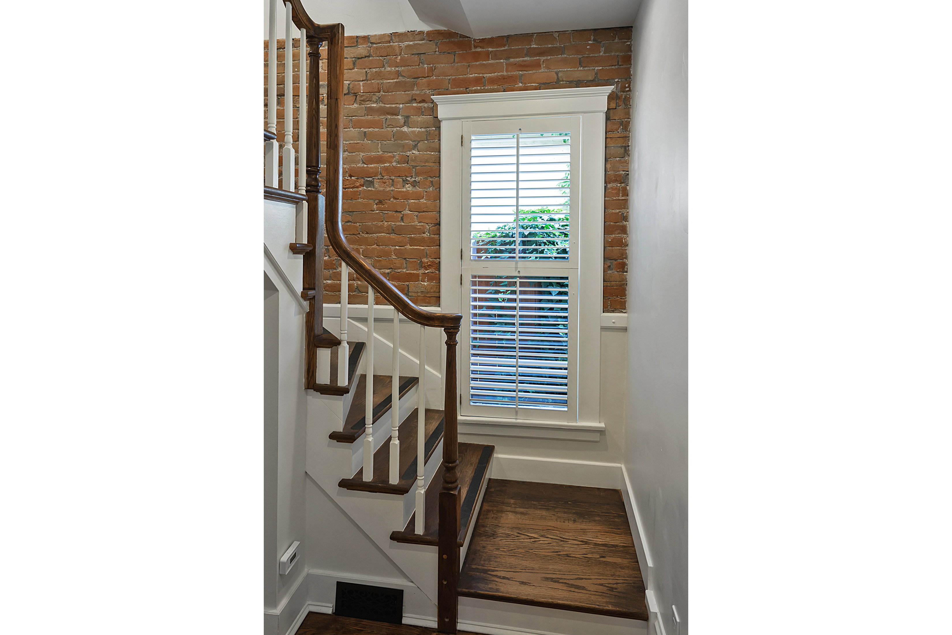 Staircase featuring rich wood-finish treads and handrail with white risers and balusters