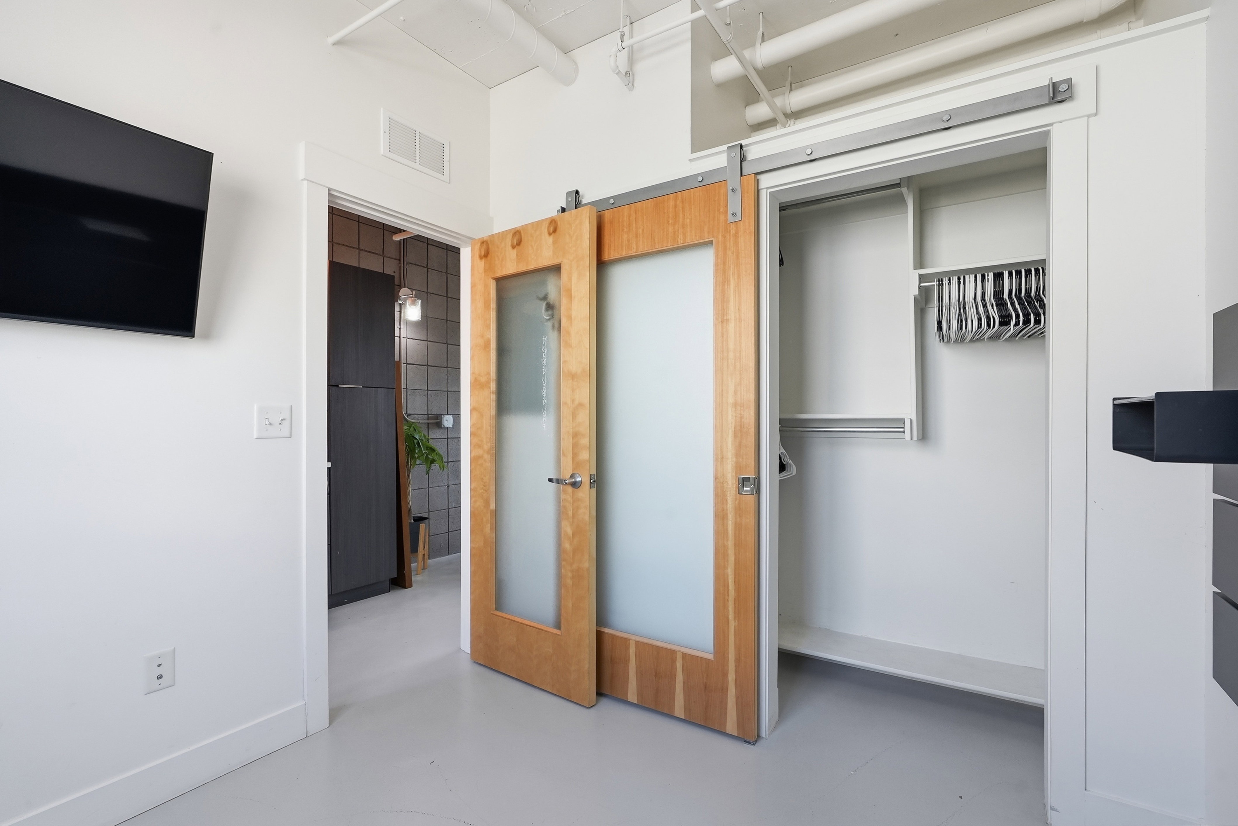 Sliding barn door with frosted glass panels opening to a closet featuring a storage system