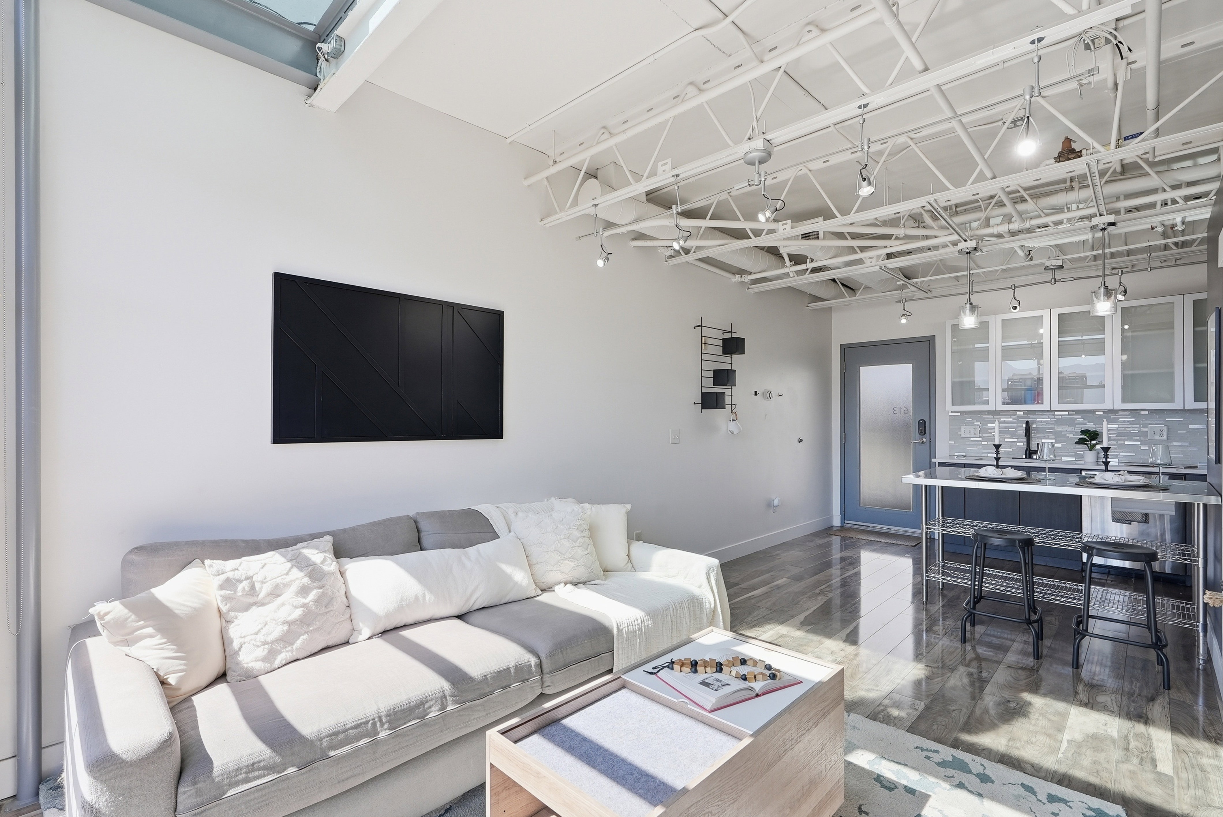 Open-concept living area with high ceilings featuring exposed ductwork and track lighting
