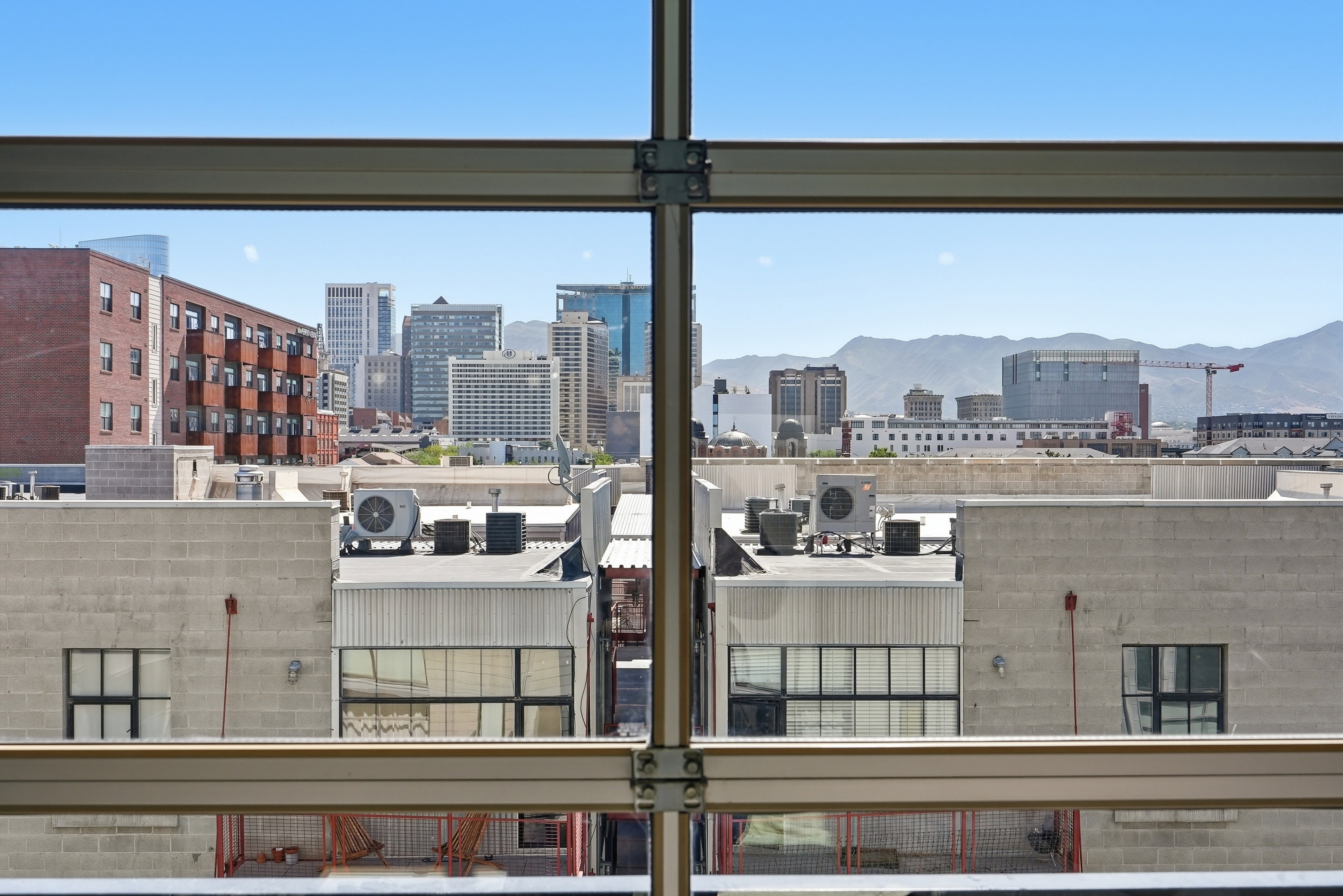 Expansive city skyline and distant mountain range framed by structural window elements