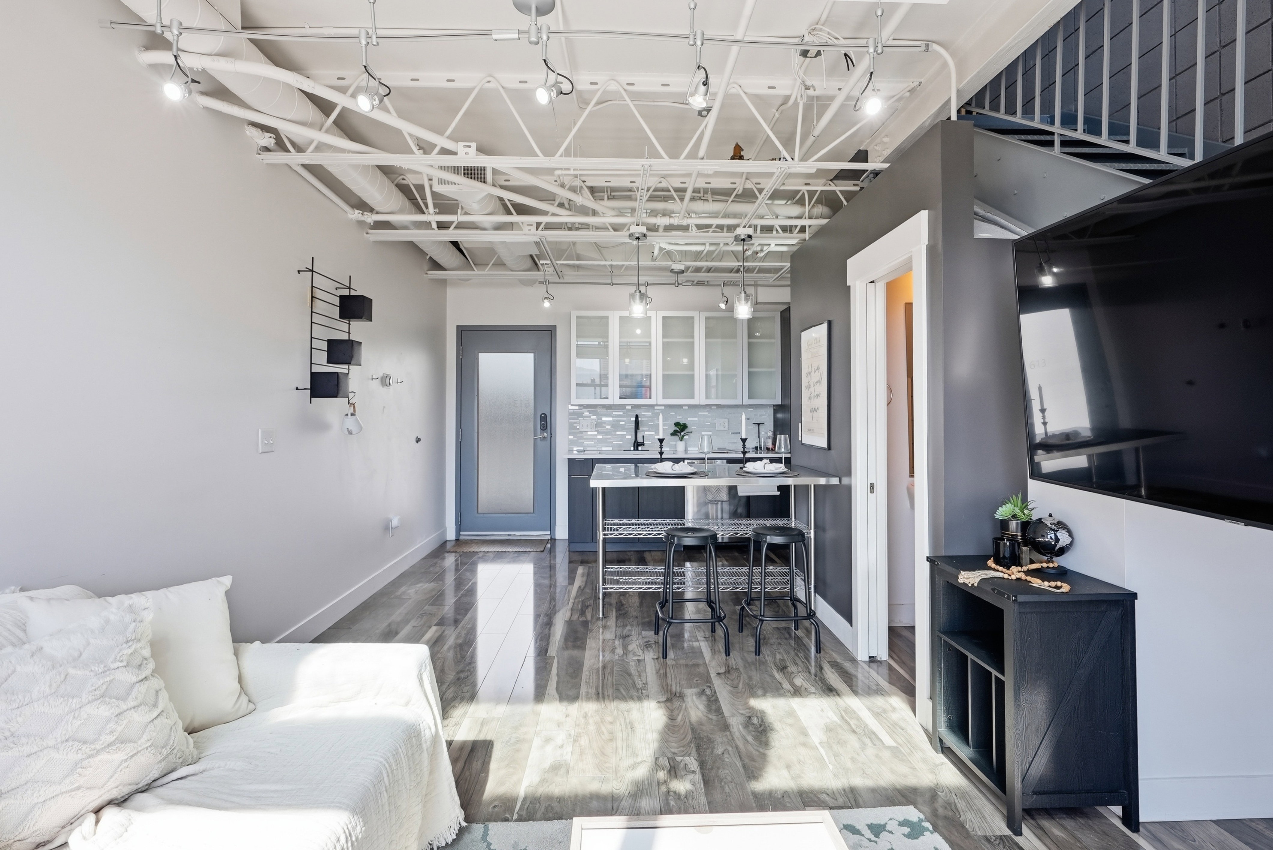 Open-concept living space with exposed ceiling trusses and track lighting