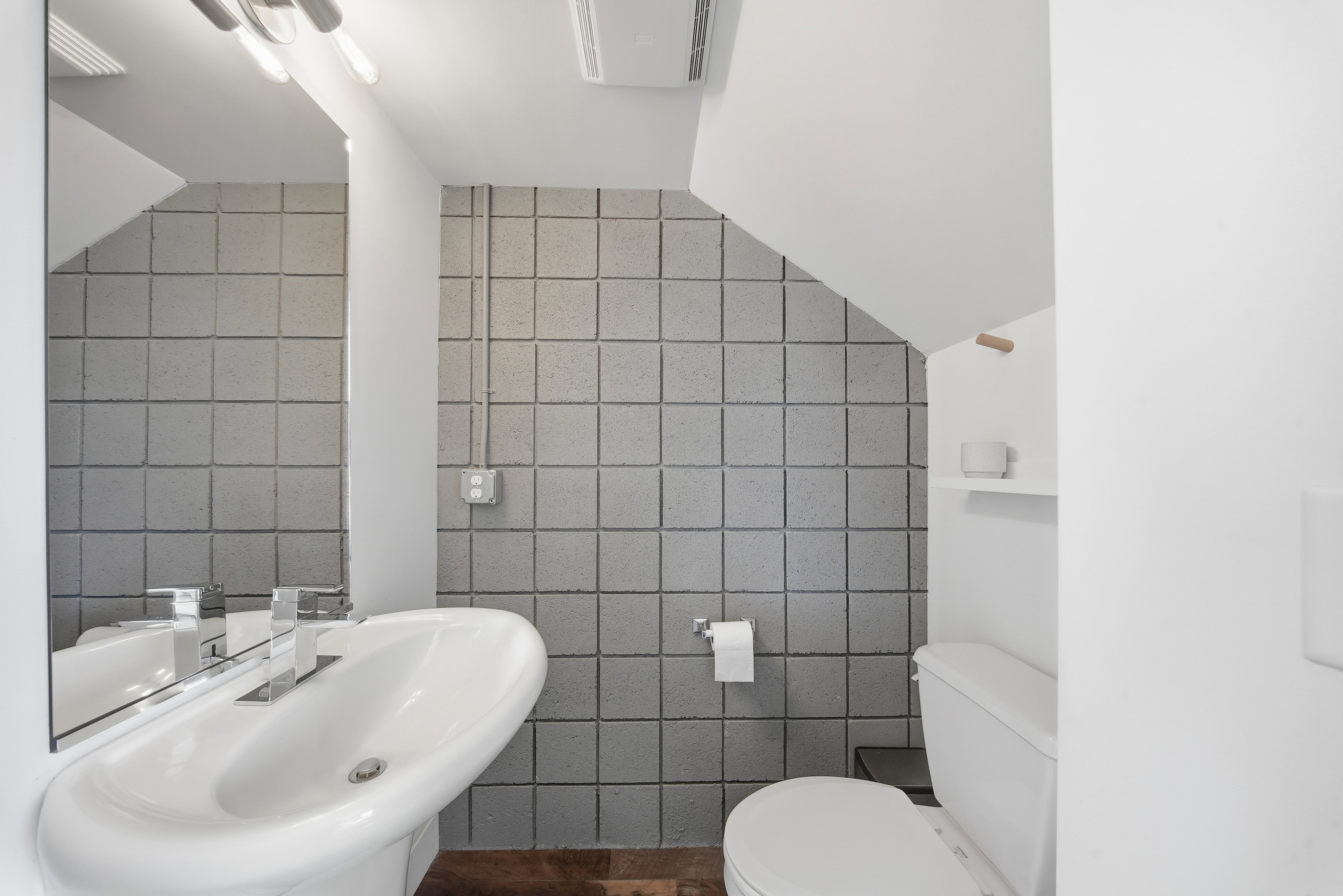 Pedestal sink with chrome faucet hardware, full-width wall mirror, and modern overhead lighting