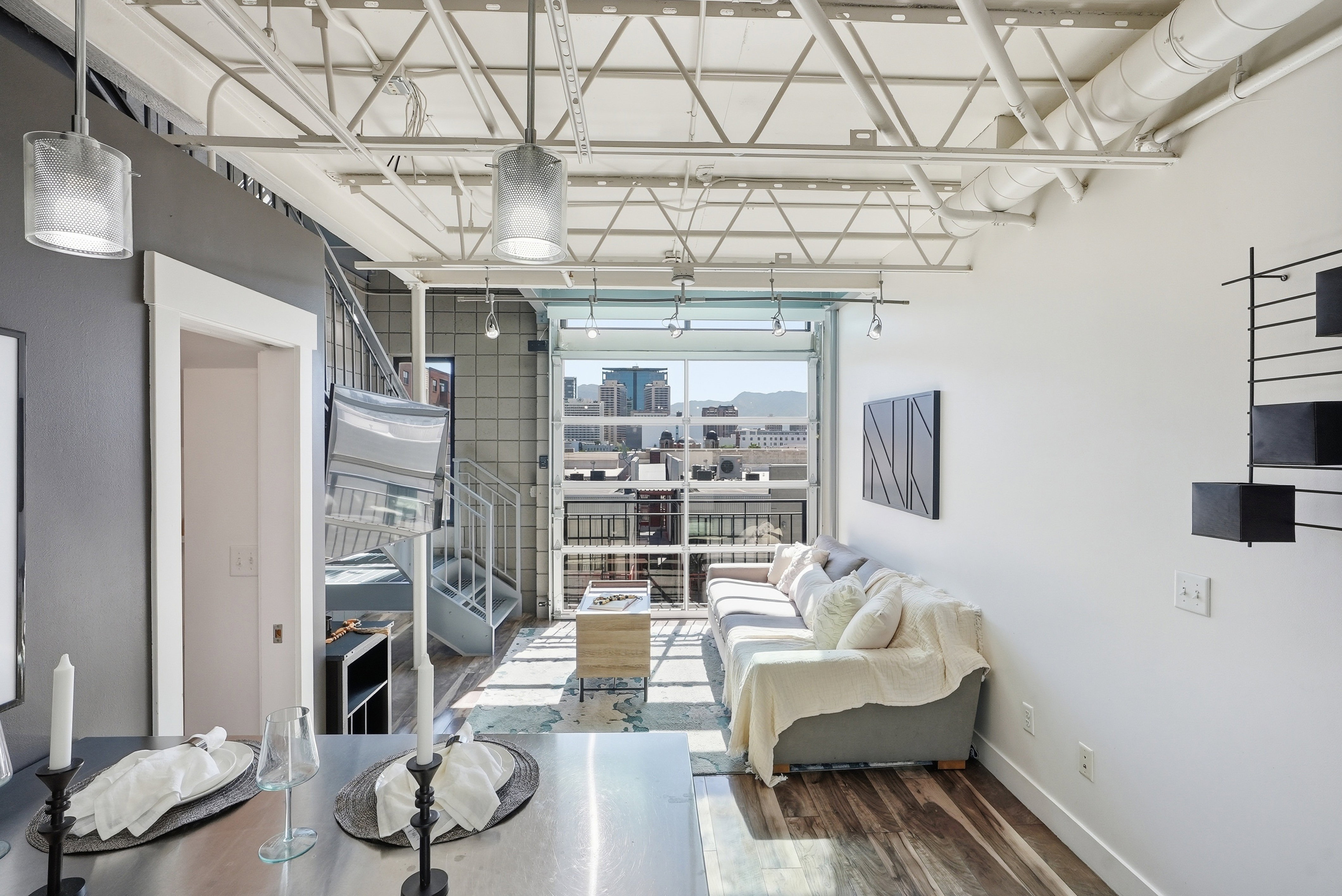 Loft-style living area featuring exposed ceiling trusses, a full-lite glass garage door, wood-finish flooring, and a spiral staircase