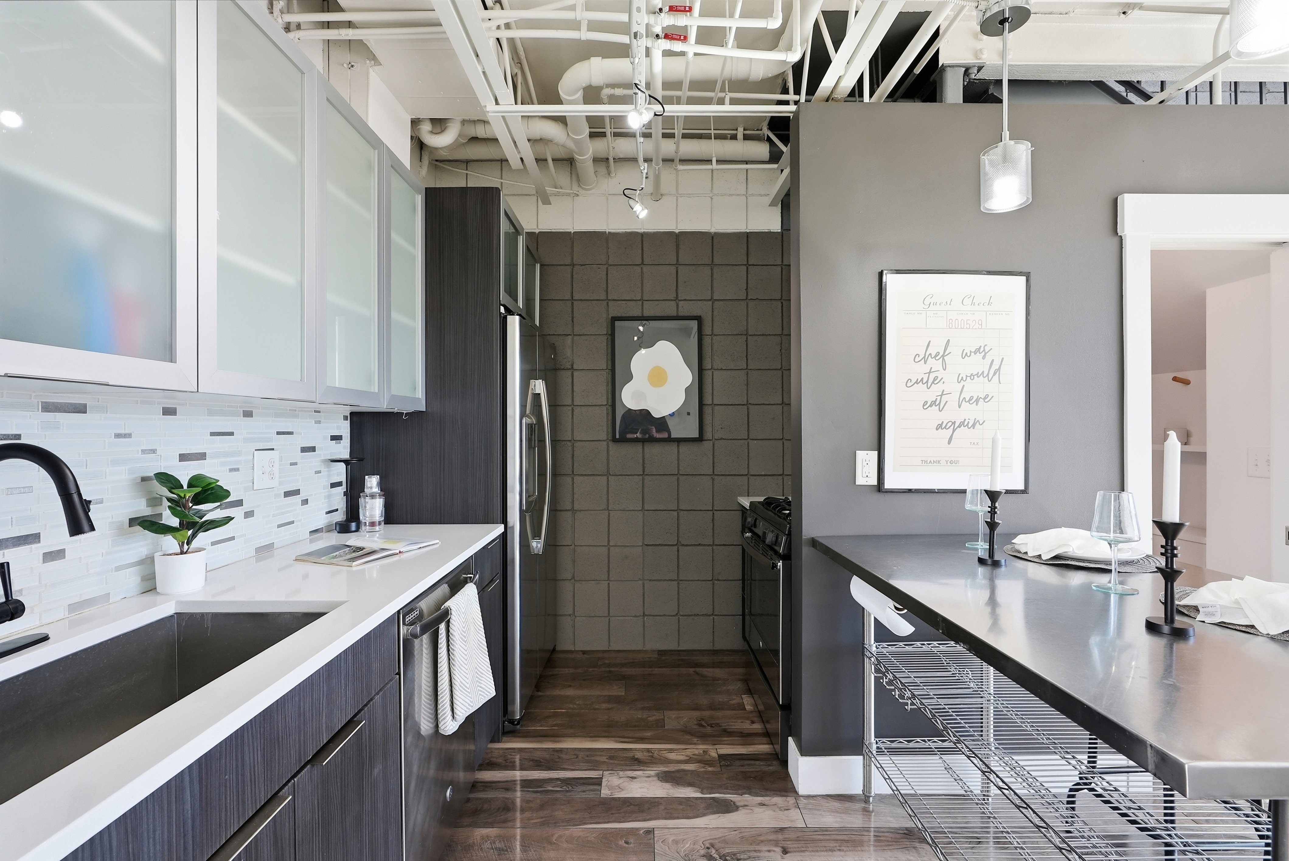 Contemporary kitchen featuring dark wood-finish cabinetry, white countertops, and a mosaic tile backsplash