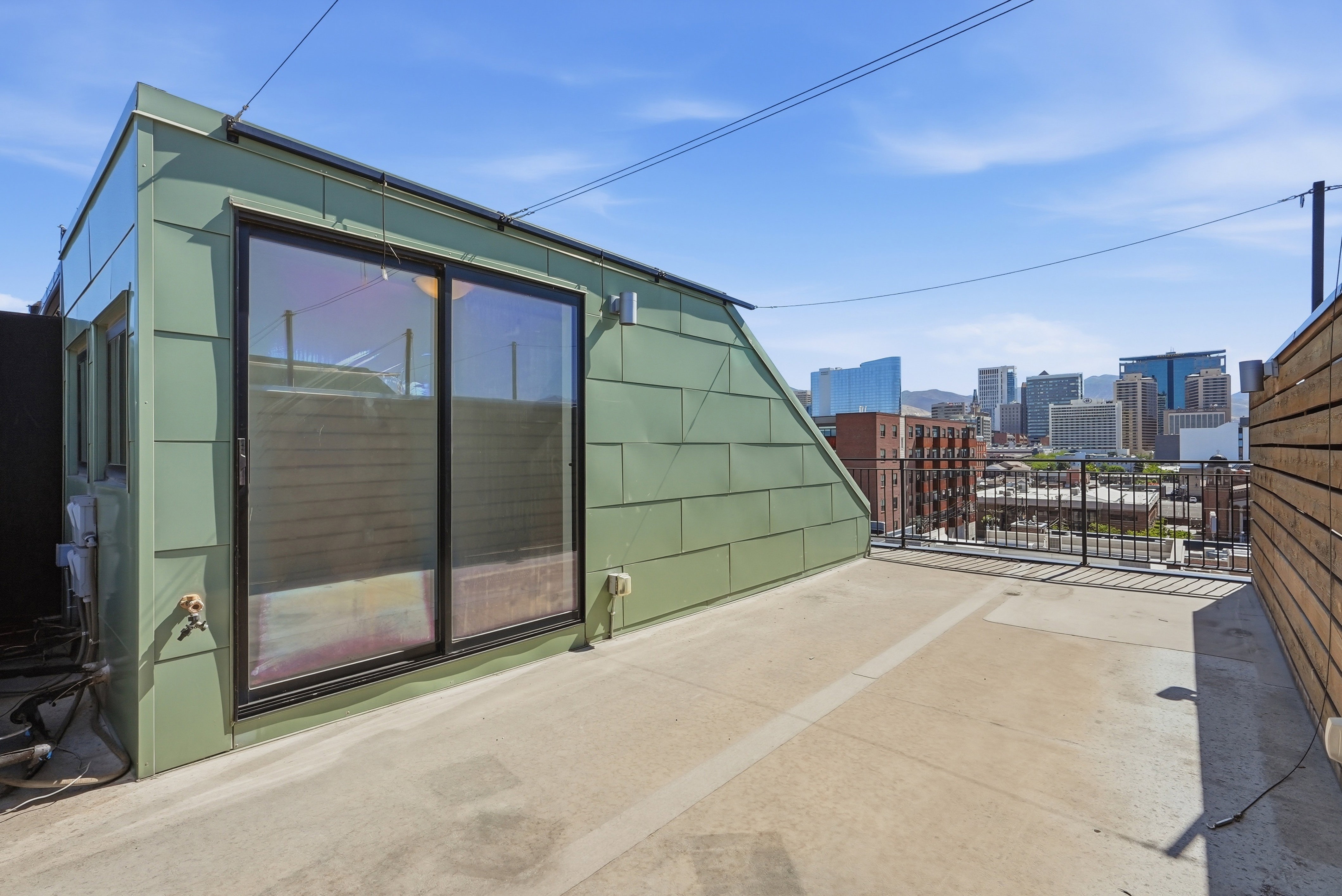 Expansive rooftop patio with concrete surfacing and a metal railing