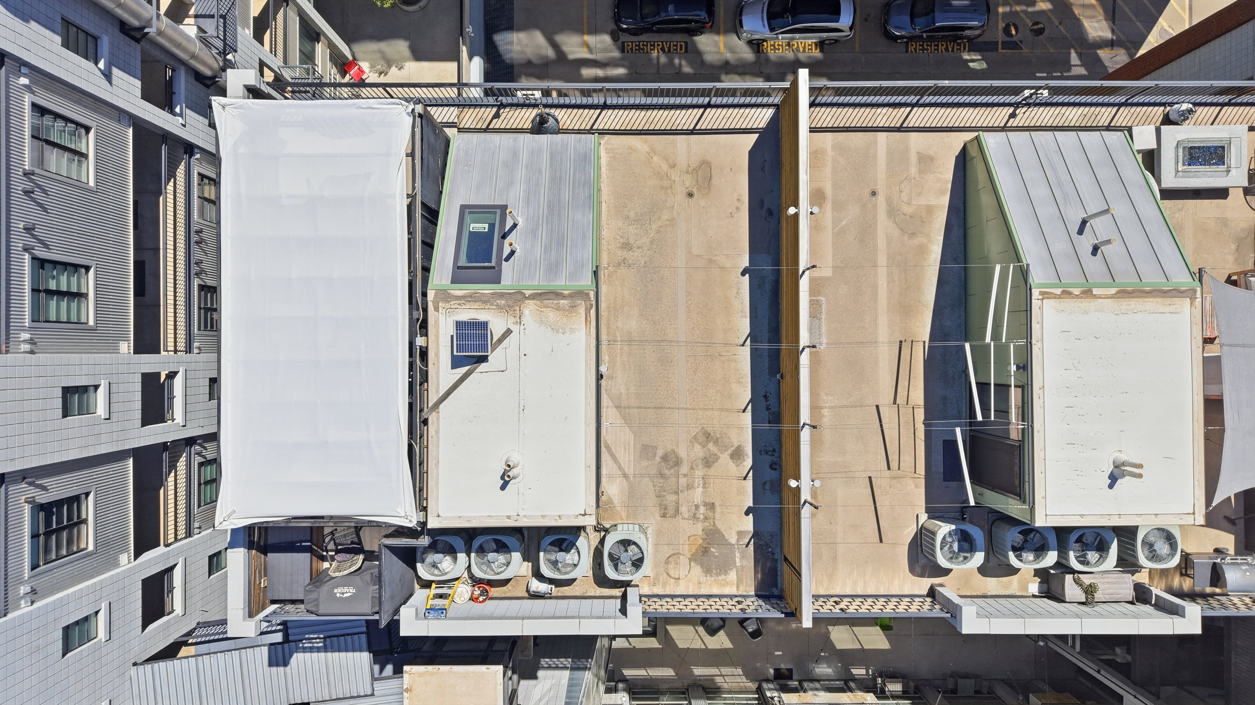 Rooftop area featuring multiple HVAC units, a large skylight, and a sloped metal roof section