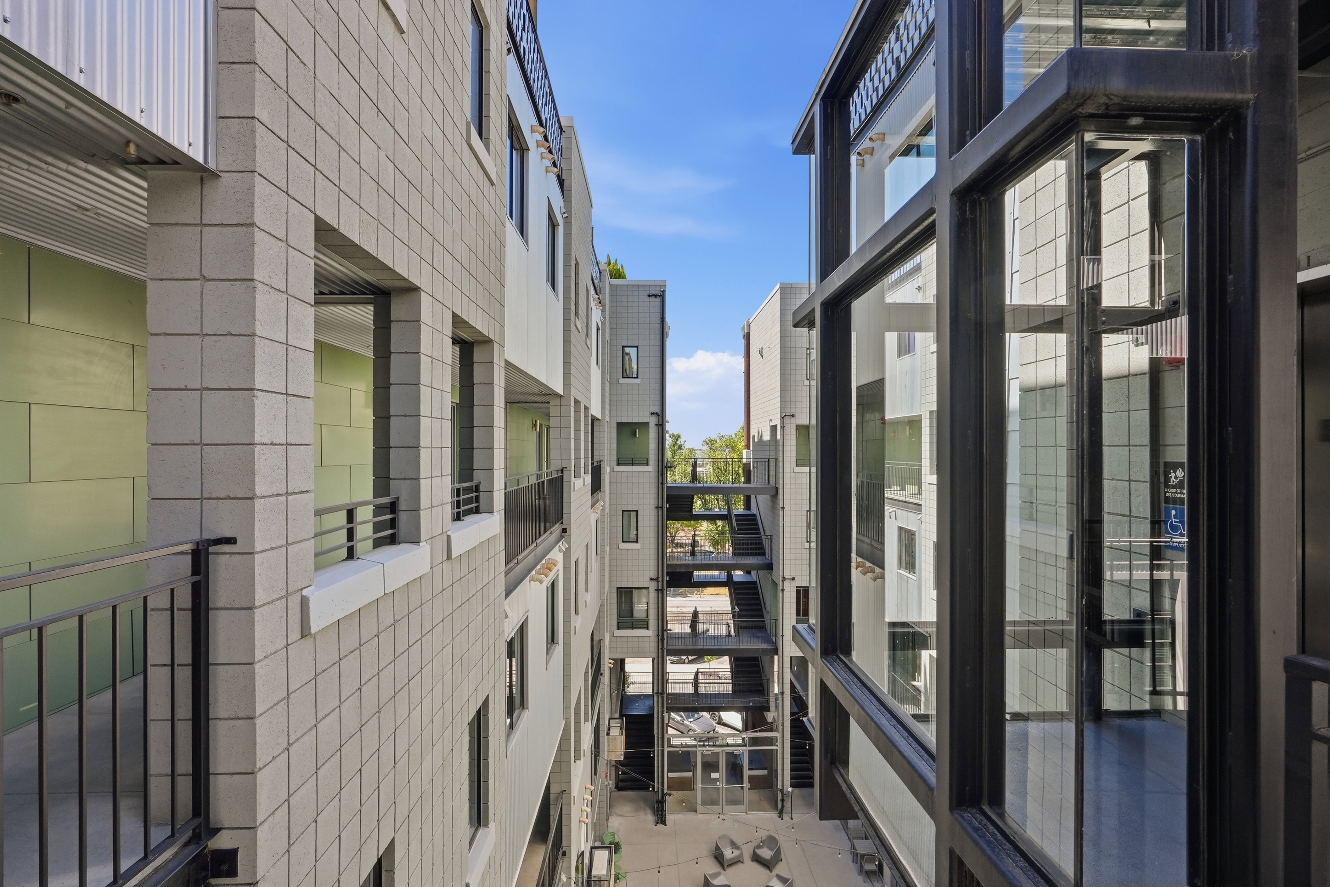Modern building exterior featuring square block facade, dark-framed windows, and metal railings