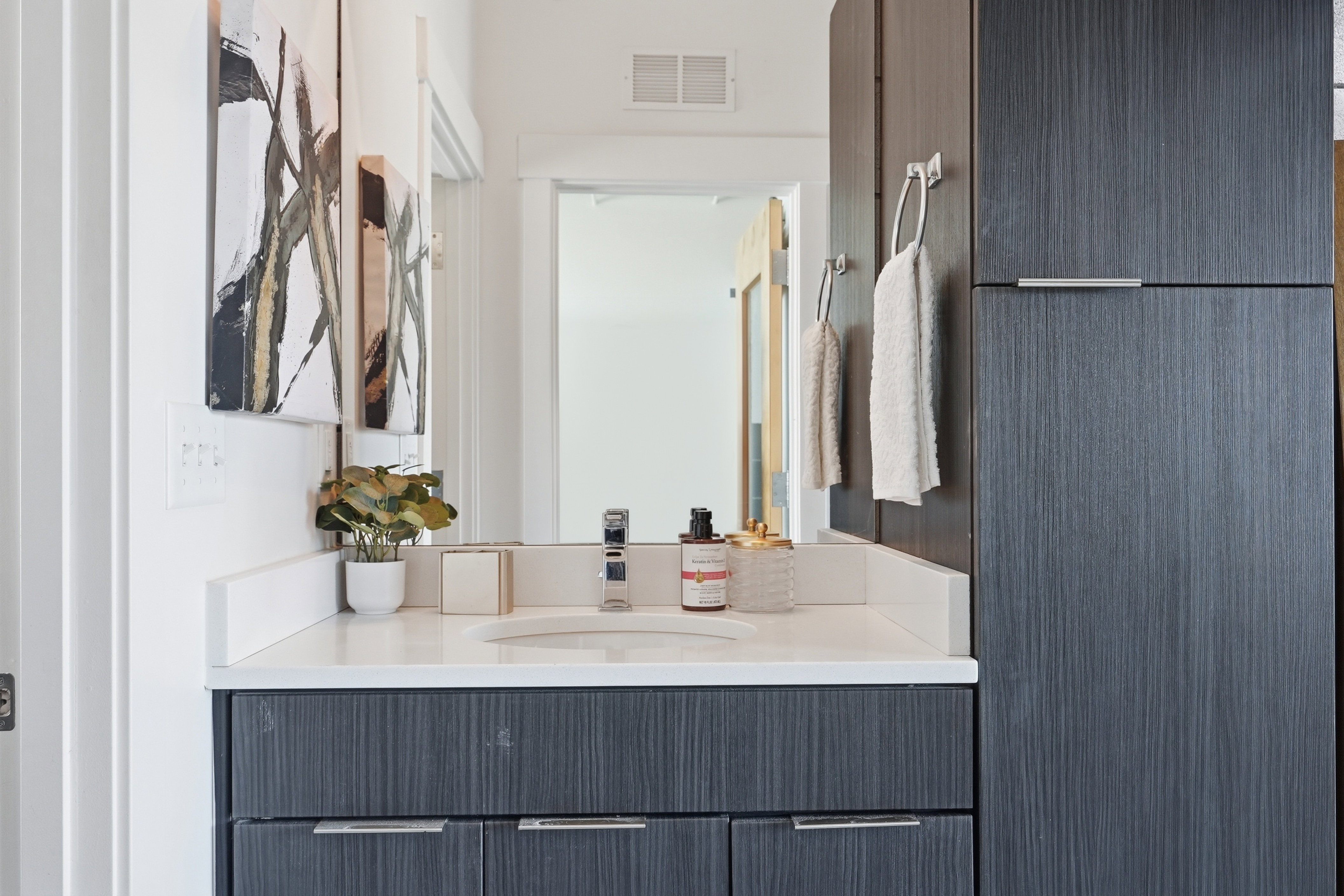 Contemporary bathroom vanity featuring a light-colored countertop with an integrated sink and a chrome faucet