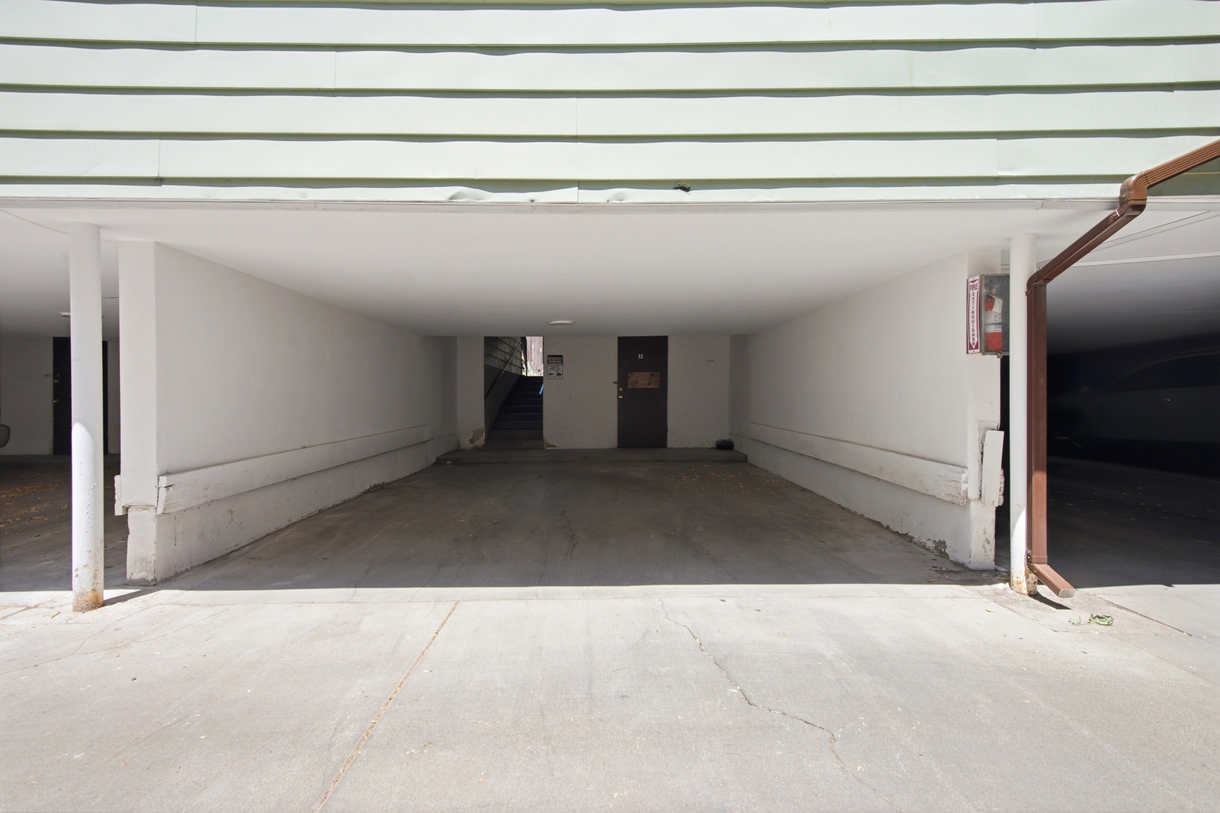 Covered parking area featuring concrete flooring and white support pillars