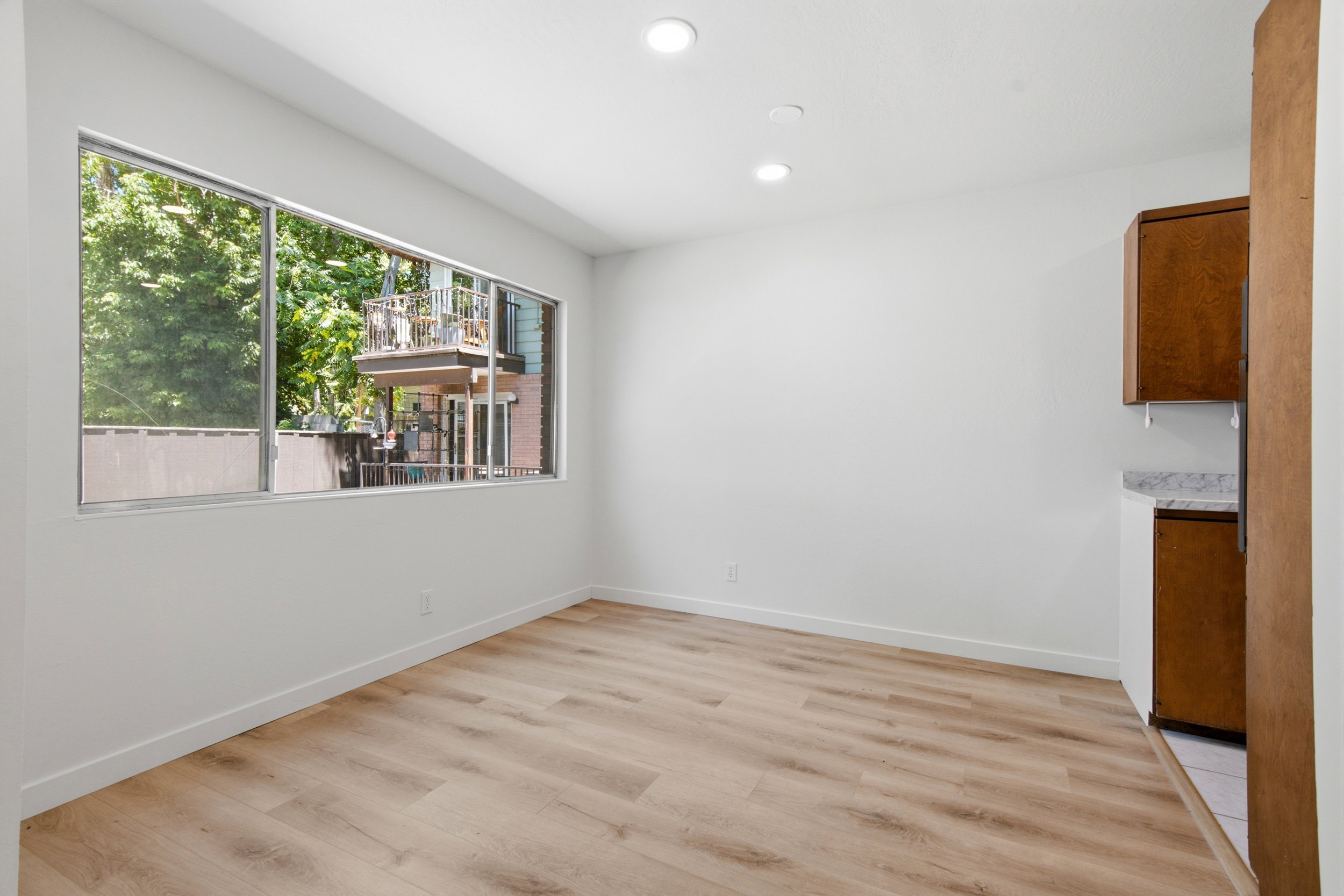 Spacious room with light wood-finish flooring, recessed lighting, and a large window