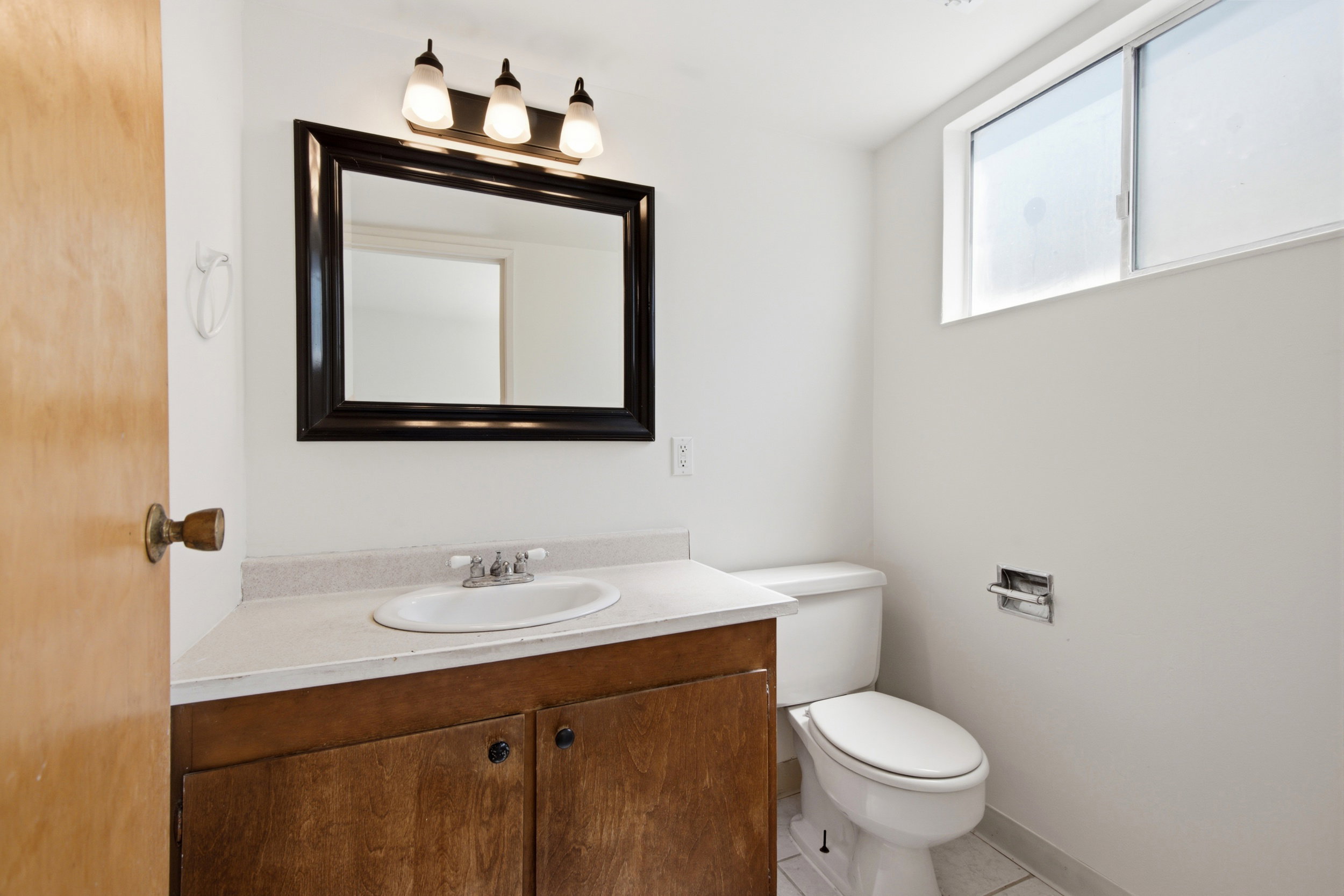 Bathroom featuring a wood-finish vanity with an integrated sink and laminate countertop
