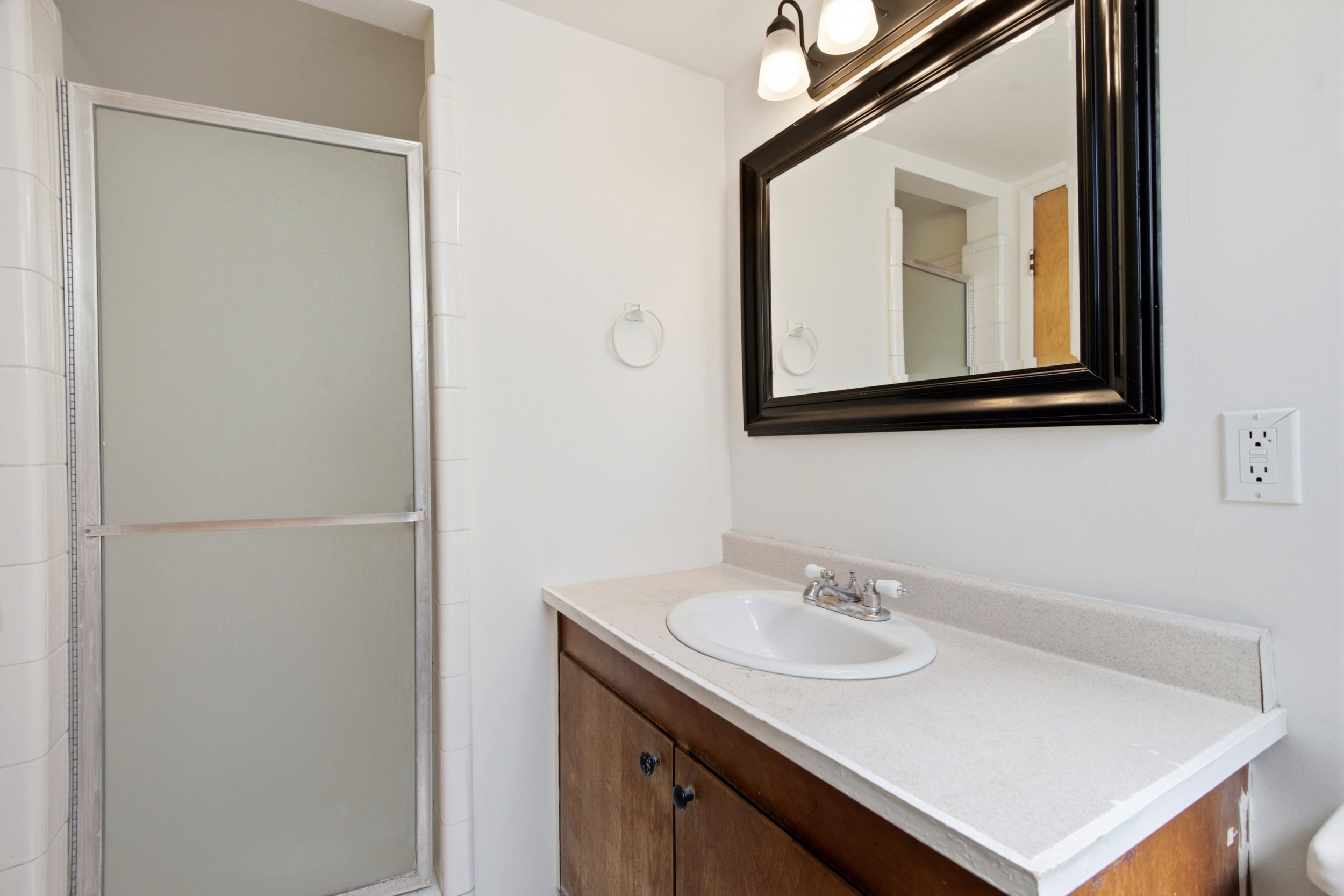 Bathroom featuring a wood-finish vanity with an integrated sink and light-toned countertop