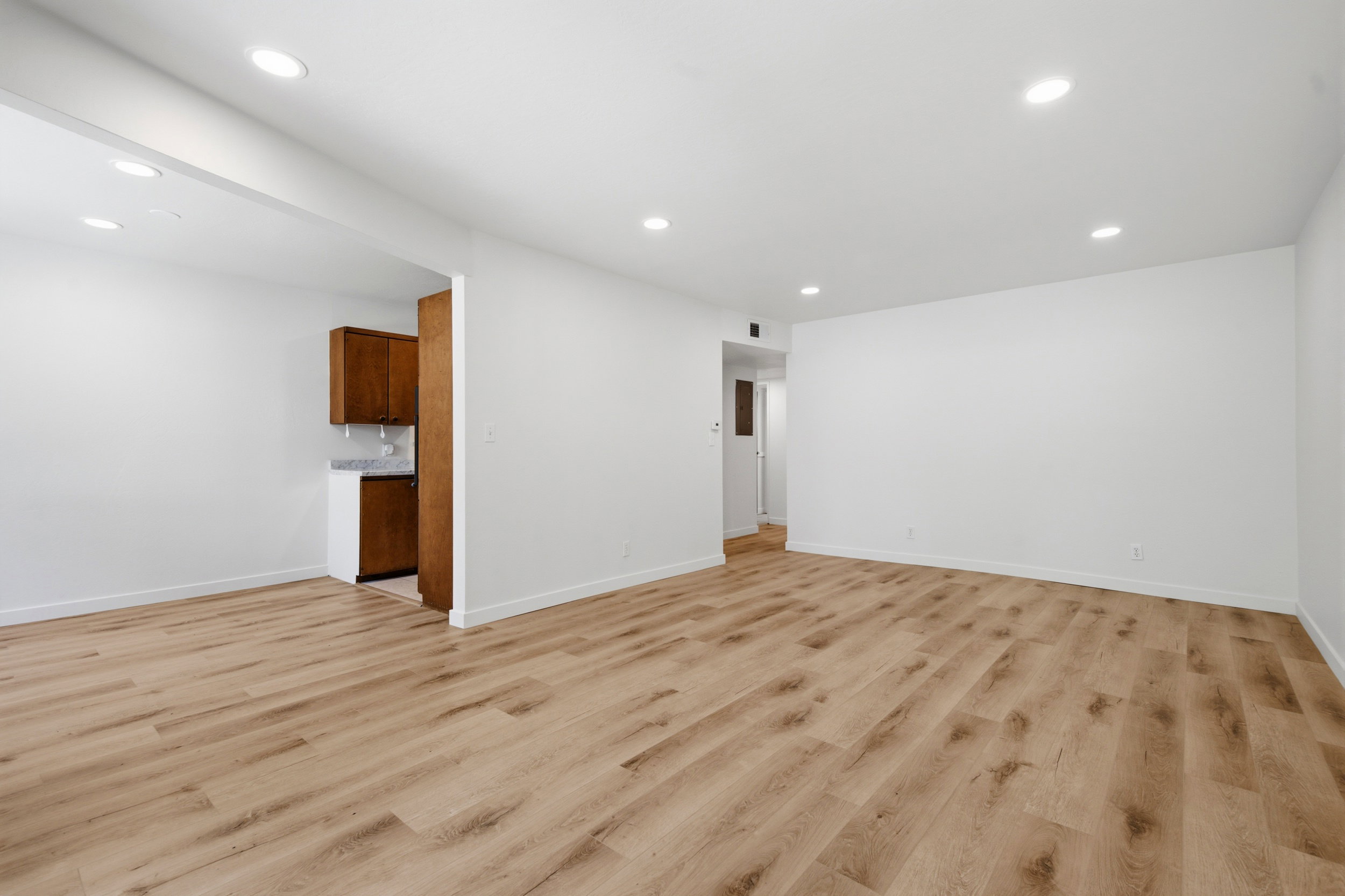 Spacious room featuring wood-finish flooring, recessed lighting, and white baseboards