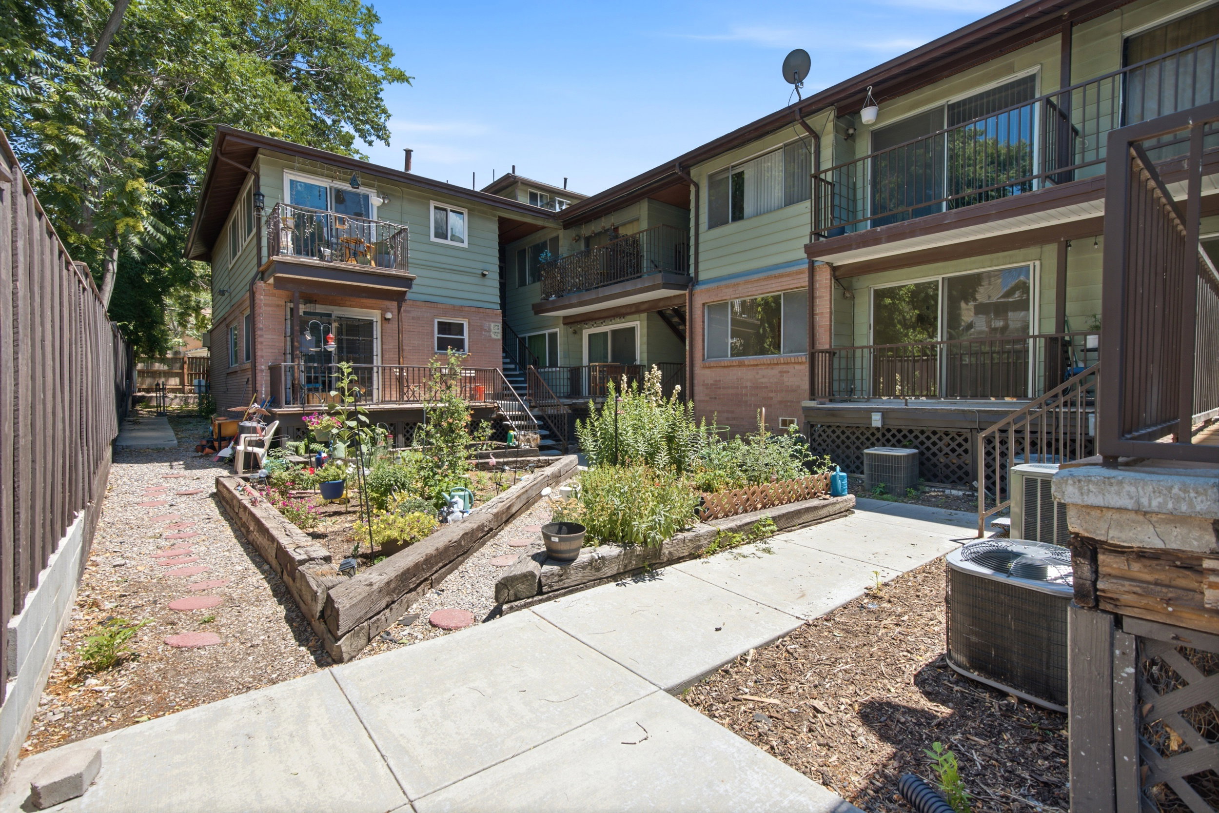 Multi-level exterior with brick and siding facade, featuring multiple balconies and ground-level patios