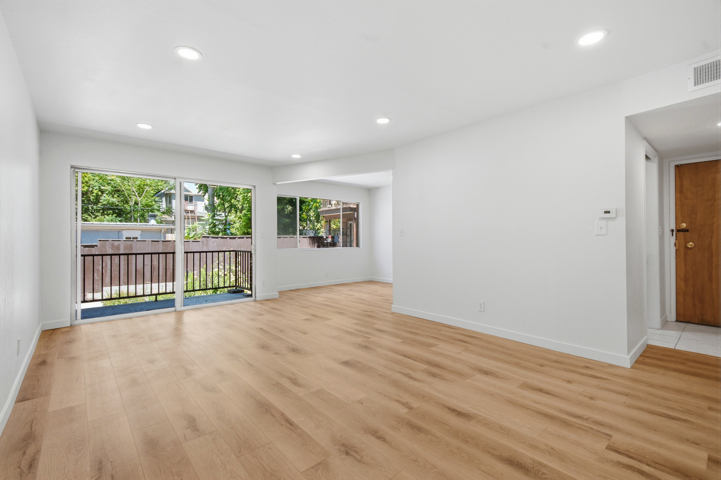 Spacious interior featuring wood-finish flooring, white walls, and recessed lighting