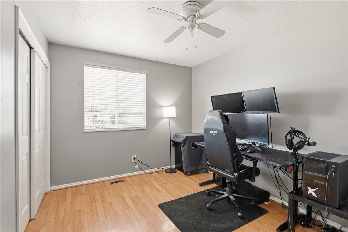 Room featuring wood-finish flooring, a ceiling fan, and a window with horizontal blinds