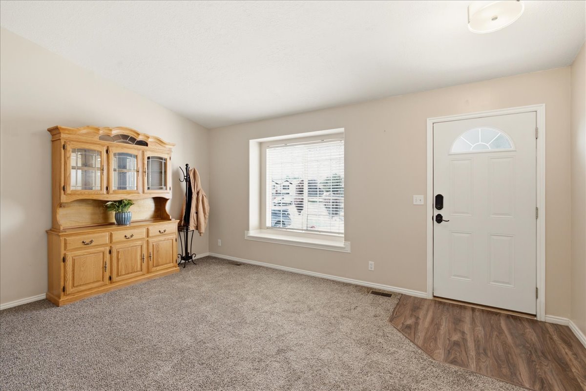 Entryway featuring a white door with a decorative transom, wood-finish flooring, and light-toned carpet