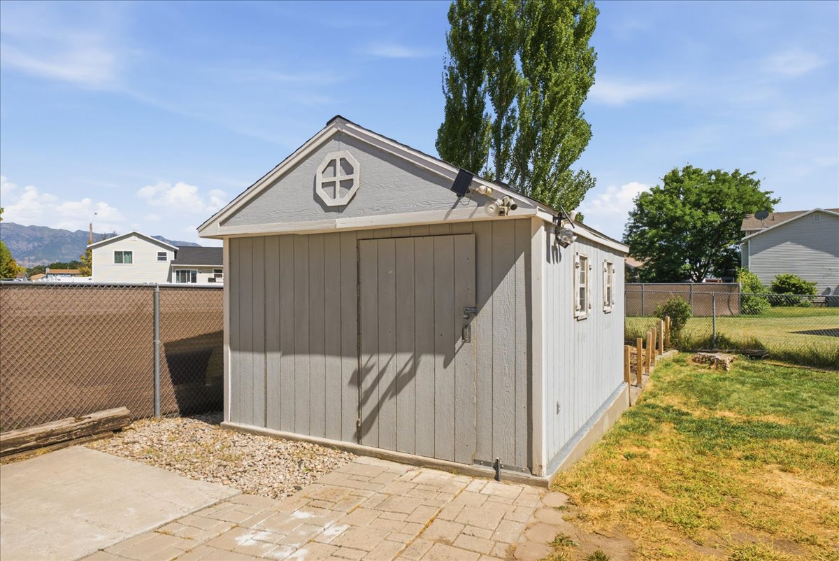 Detached storage shed featuring vertical siding, a gable roofline, and an octagonal window detail