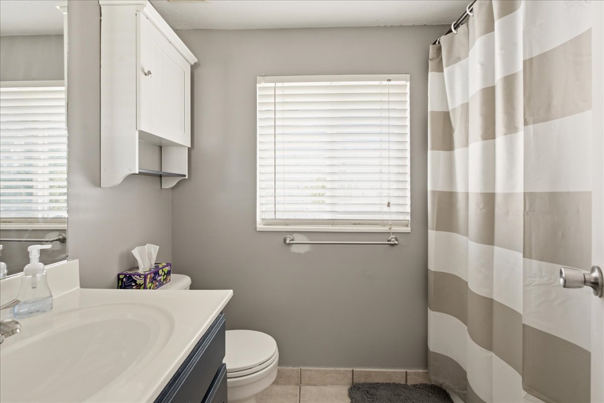 Bathroom featuring a single vanity with an integrated sink, white countertop, and dark cabinetry